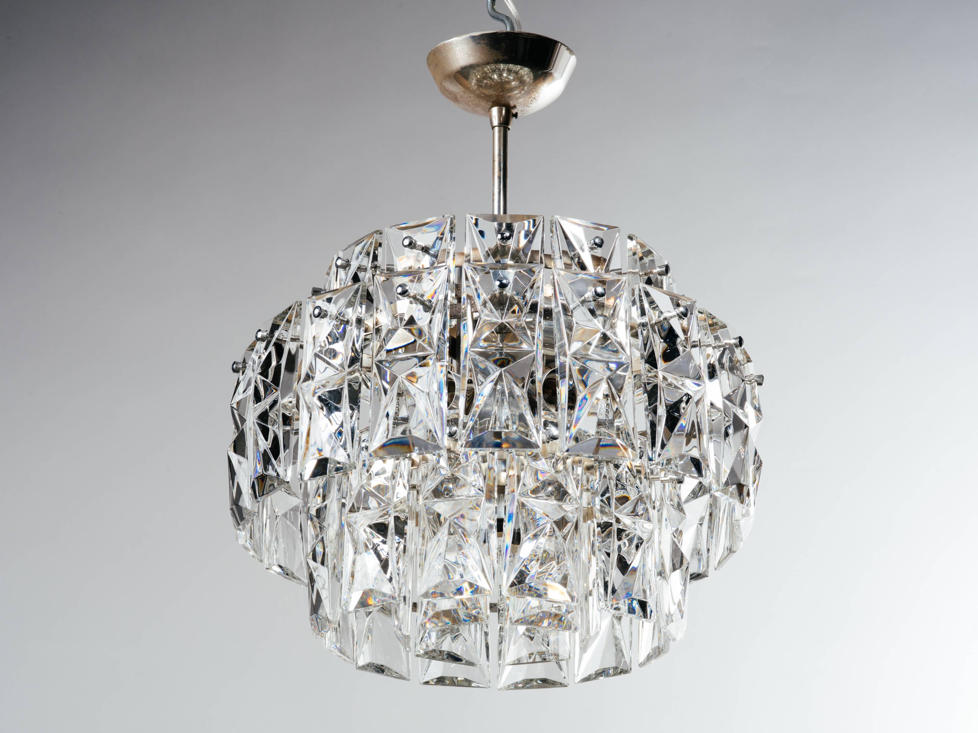 Mid-Century Modern chandelier by German manufacture Kinkeldey, known for their iconic faceted and cut crystal designs. This light fixture features a multiple tier design with single and double length faceted crystal prisms. Chrome frame and stud