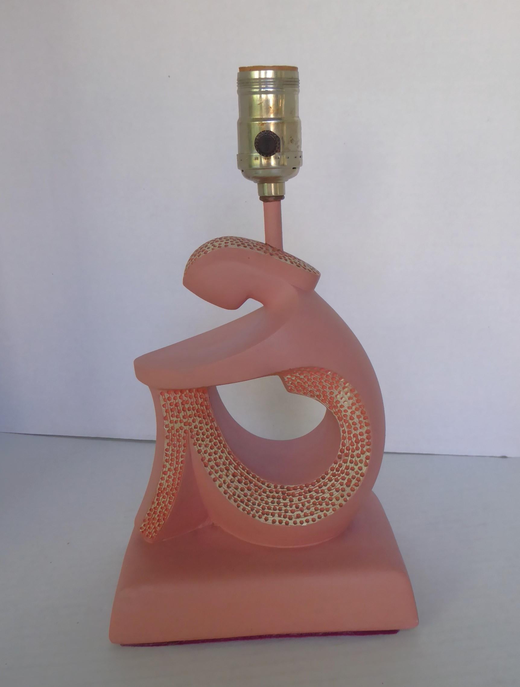 Mid Century Modern small plaster or chalkware table lamp of stylized seated Lady in pink from the 1950s.  The white partial body front and hair with pink pin pricks adding a nice texture. Incised on the bottom back F.A.I.P. Add your own shade. 