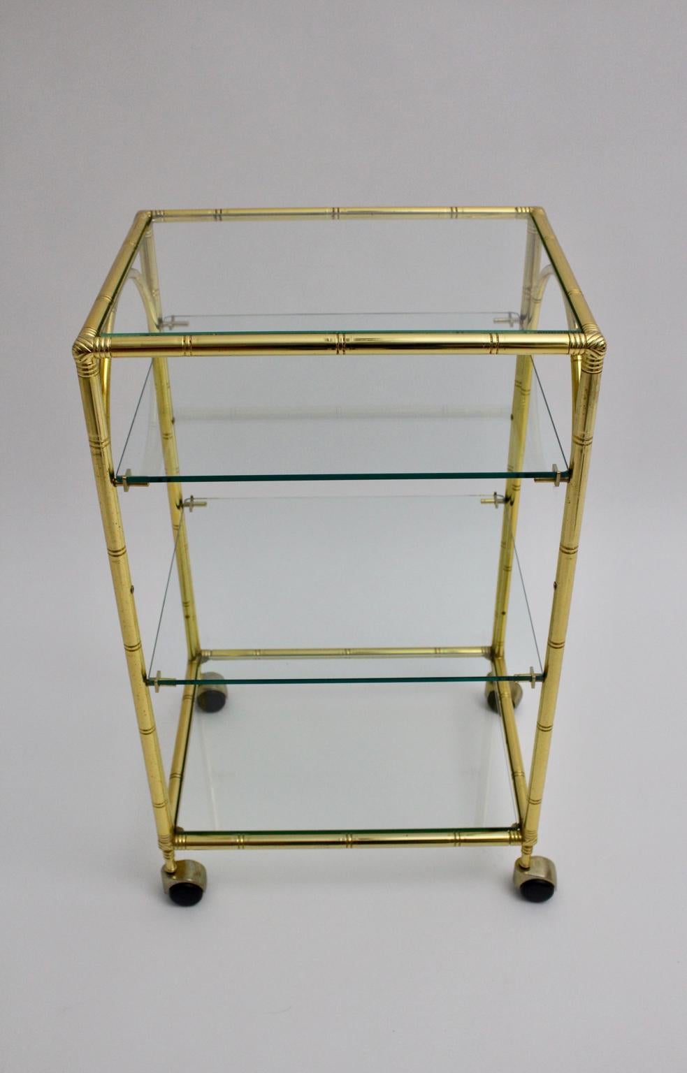 Carrello da bar in finto bambù vintage in metallo dorato di Vintage By  Francia anni '60 con quattro piatti di vetro e quattro ruote.
Le lastre di vetro non presentano scheggiature o danni.
Le condizioni sono buone con lievi segni dell'età.
misure