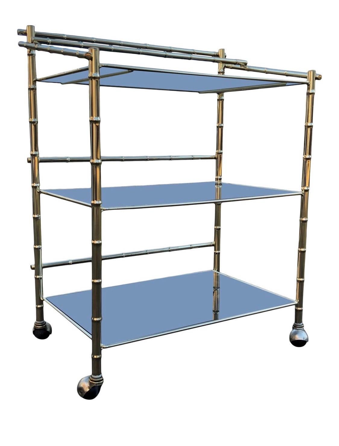 Elegant brass and smoked glass faux bamboo rolling bar cart. The smoked glass shelving is removable and everything is original. Very good vintage condition with little oxidation or pitting. Glass is in decent age appropriate condition. 

Believed