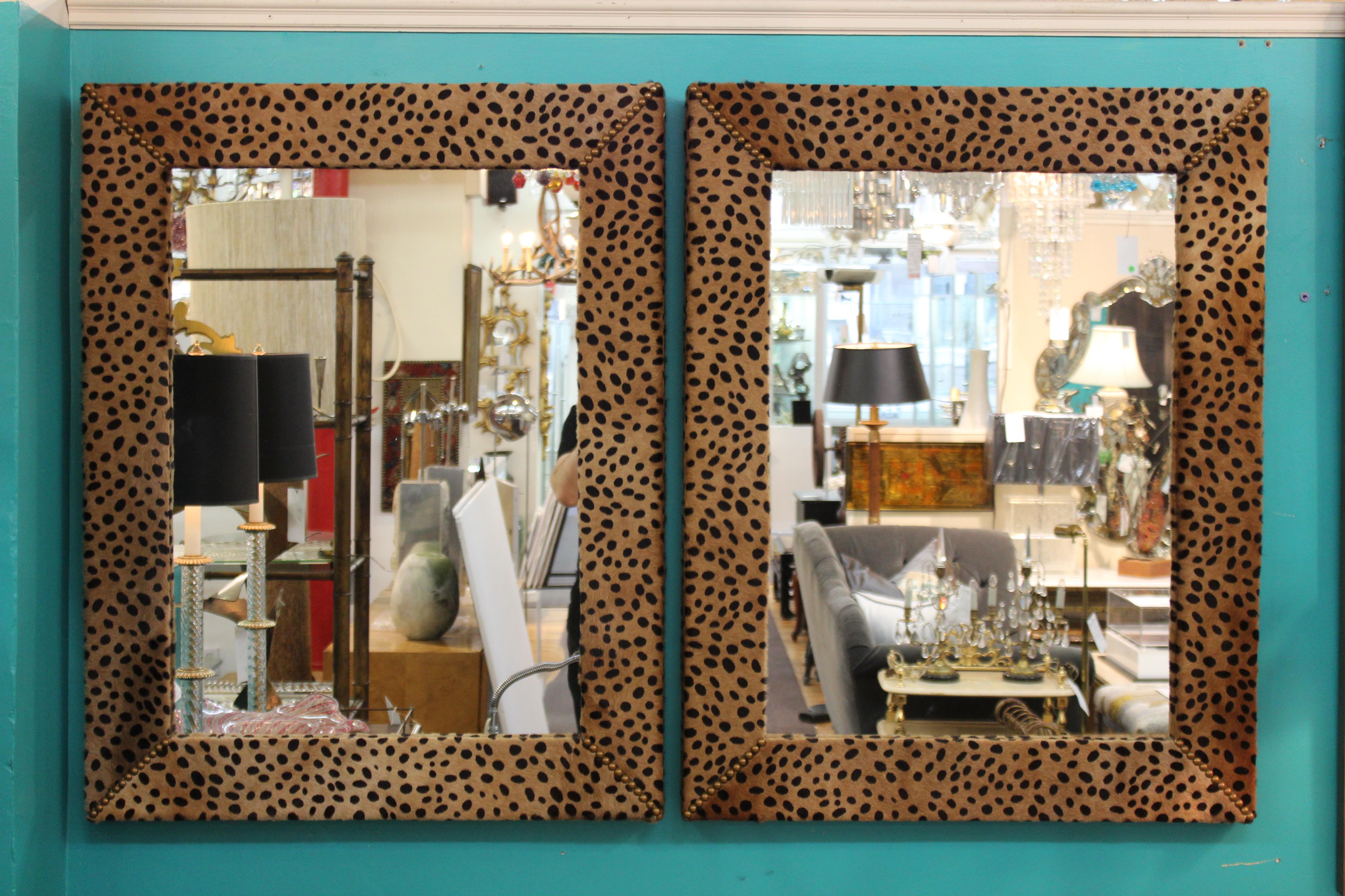 Mid-Century Modern pair of mirrors framed with faux leopard leather with brass nailheads. The pair is in great vintage condition and was made in the United States during the 1970s.
