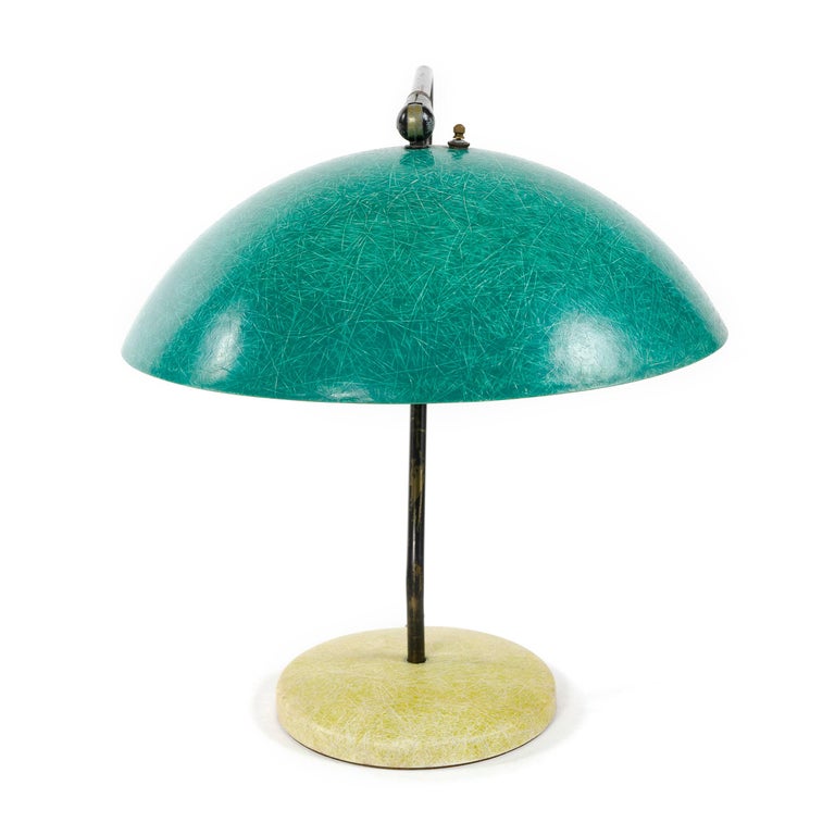Classic form midcentury table or desk lamp consisting of a green fiberglass spherical shade attached with a swivel device to a black, tubular metal stem shaped to conform to the shade. The stem is set in a heavy cast iron loader (weight) which is