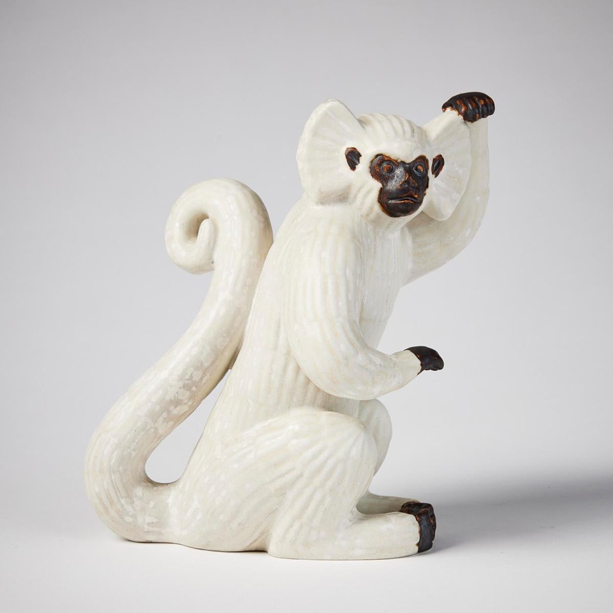 Rare figurine scandinave moderne de Gunnar Nylund représentant un singe Gibbon à carreaux, de Rörstrand, Suède, années 1940. Sculpture avec glaçure coquille d'oeuf et un support en bois. Signé R SWEDEN G.N. Hauteur 17,5 cm. Très bon état. Usure