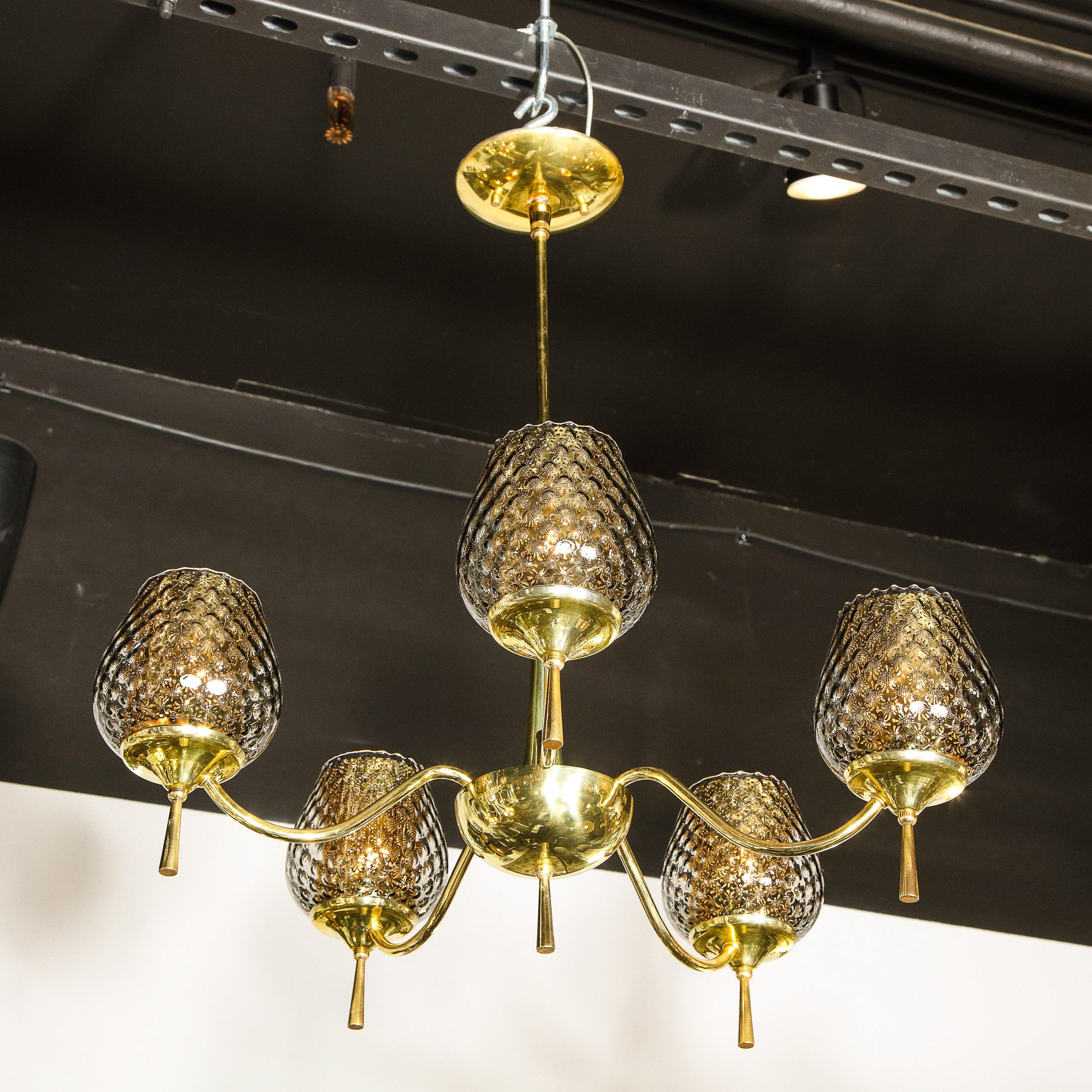 This stunning Mid Century Modern chandelier was realized in Murano, Italy- the island off the coast of Venice renowned for centuries for its superlative glass production, circa 1960. It features a brass hourglass form body that connects to domed