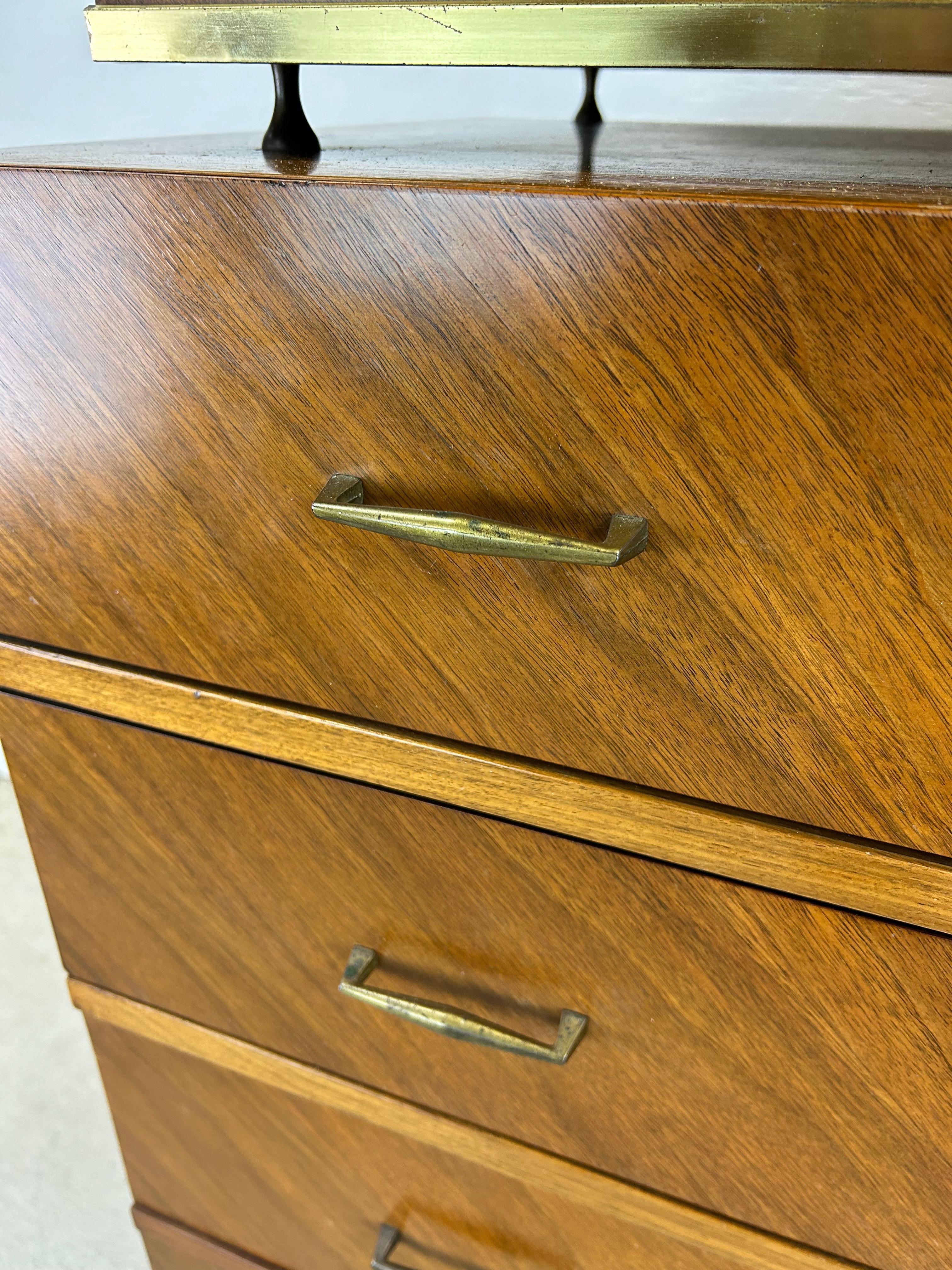Questo comò highboy di metà secolo presenta una struttura in legno massiccio, una bella impiallacciatura in noce con venature uniche, sei cassetti a coda di rondine, due nel mobile, quattro sotto con ferramenta in ottone e alte gambe affusolate.