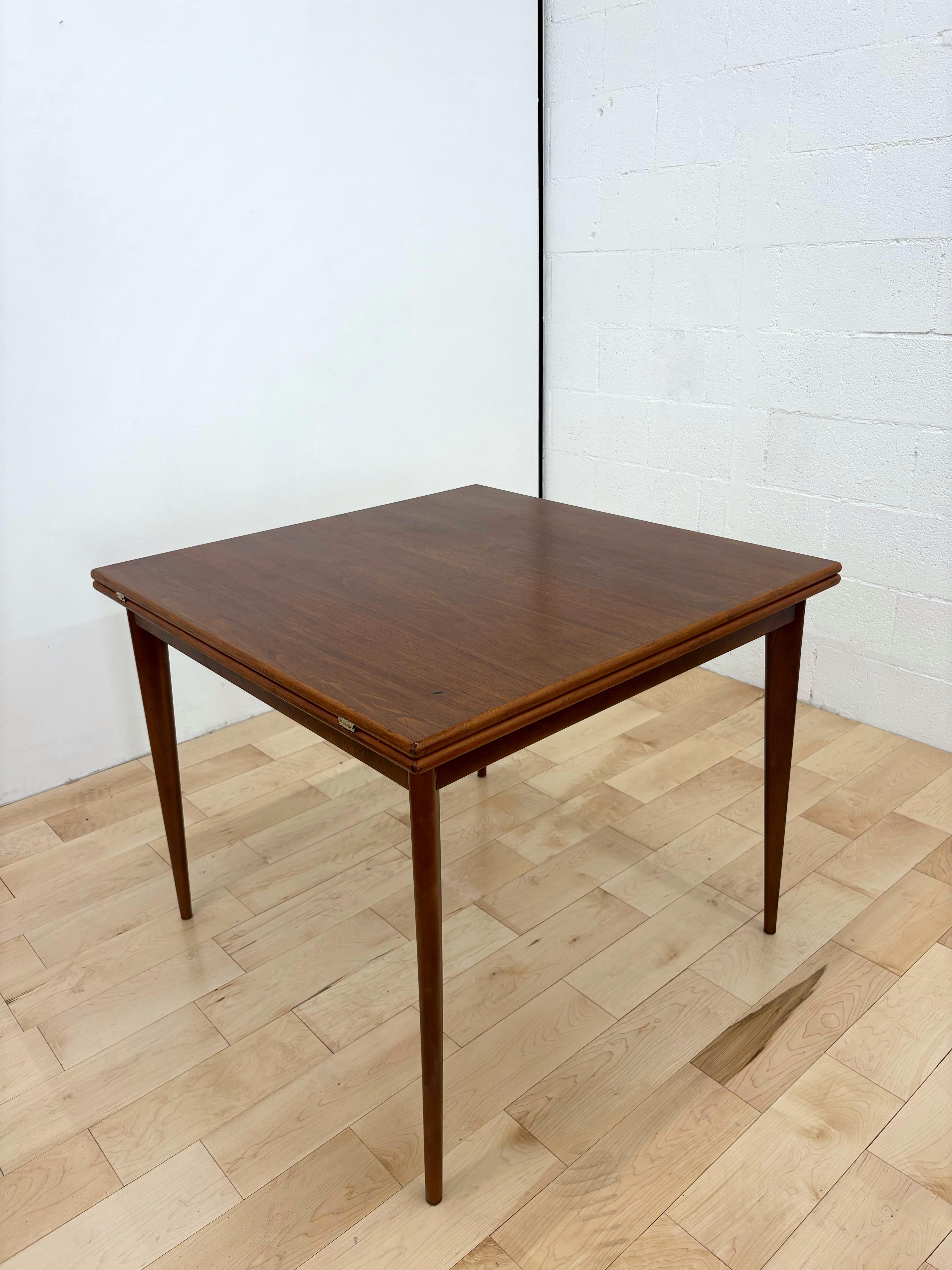 An original mid-century Teak and walnut flip top dining table with solid brass brackets. The table can easily be expanded from square to rectangle by pulling the top to one side and flipping one piece over.
The top square surface is teak, however