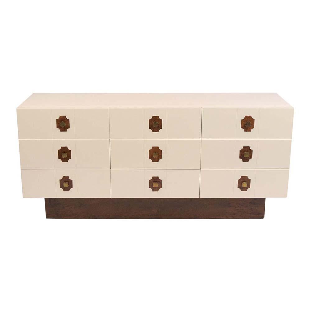 This Vintage Mid-Century Modern Dresser has been completed restored and stained in a rich dark walnut & ivory color combination with a newly lacquered finish. This chest of drawers features nine drawers with Trevol design burled insert in the center