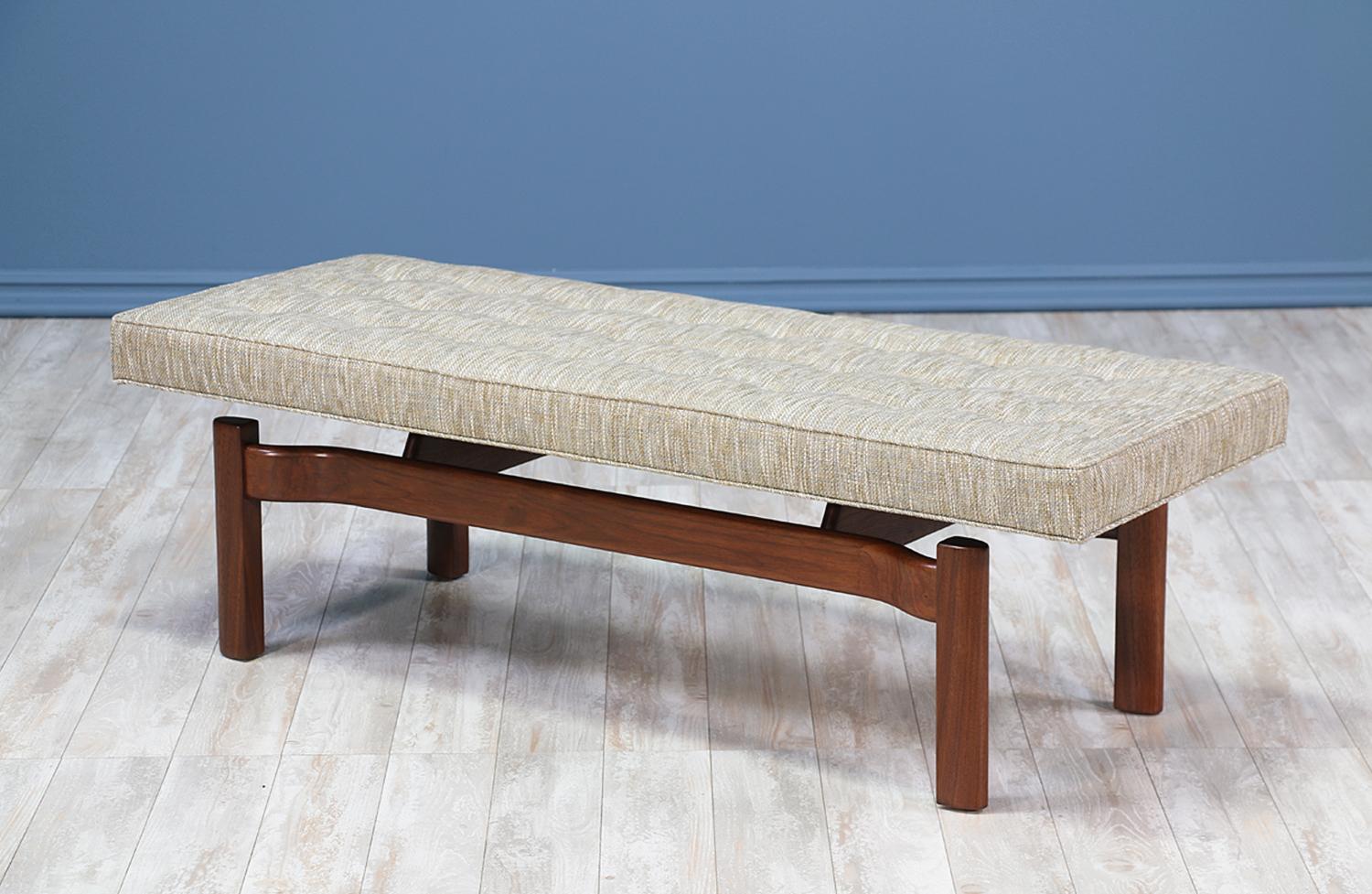 Mid-Century Modern bench designed and manufactured in the United States, circa 1950s. Solid walnut wood base holds a newly reupholstered cushion in a muted grey tweed fabric creating a floating illusion. Fantastic design perfect for any