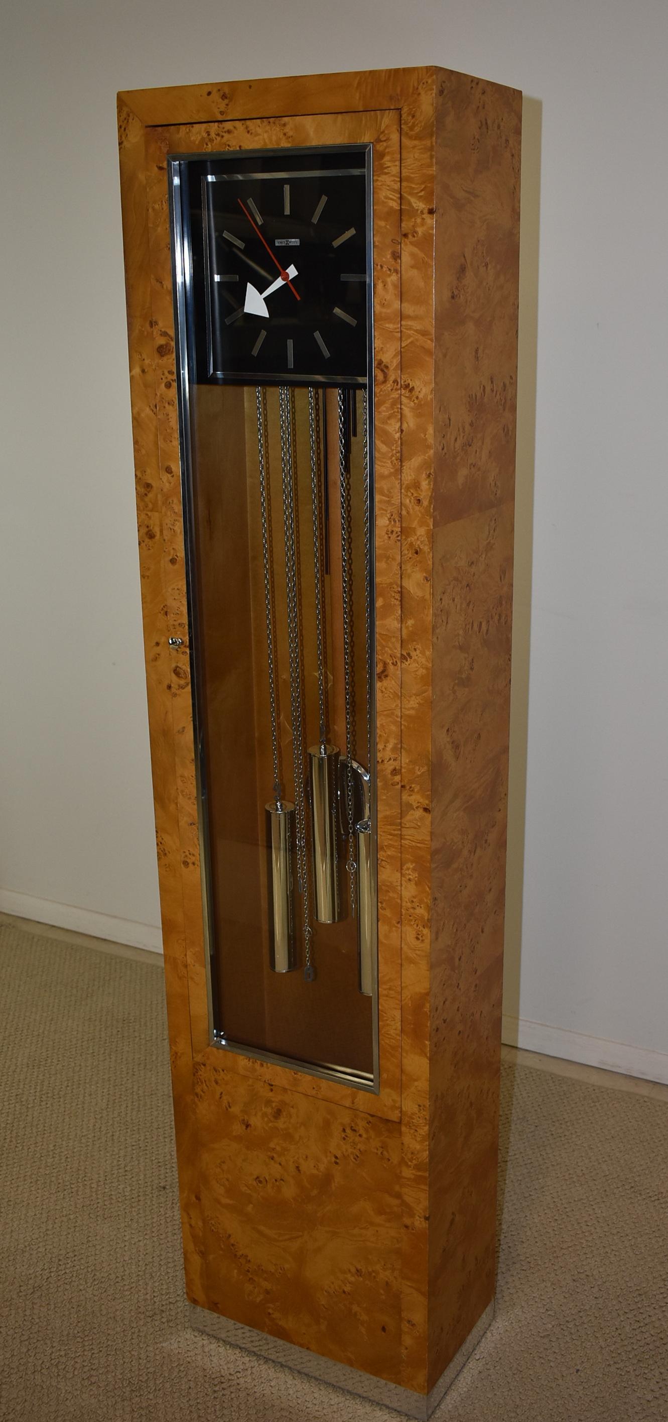 Mid-Century Modern olivewood case Howard Miller floor clock. Chrome base. Runs. Chimes need to be adjusted. Very good condition. Dimensions: 9