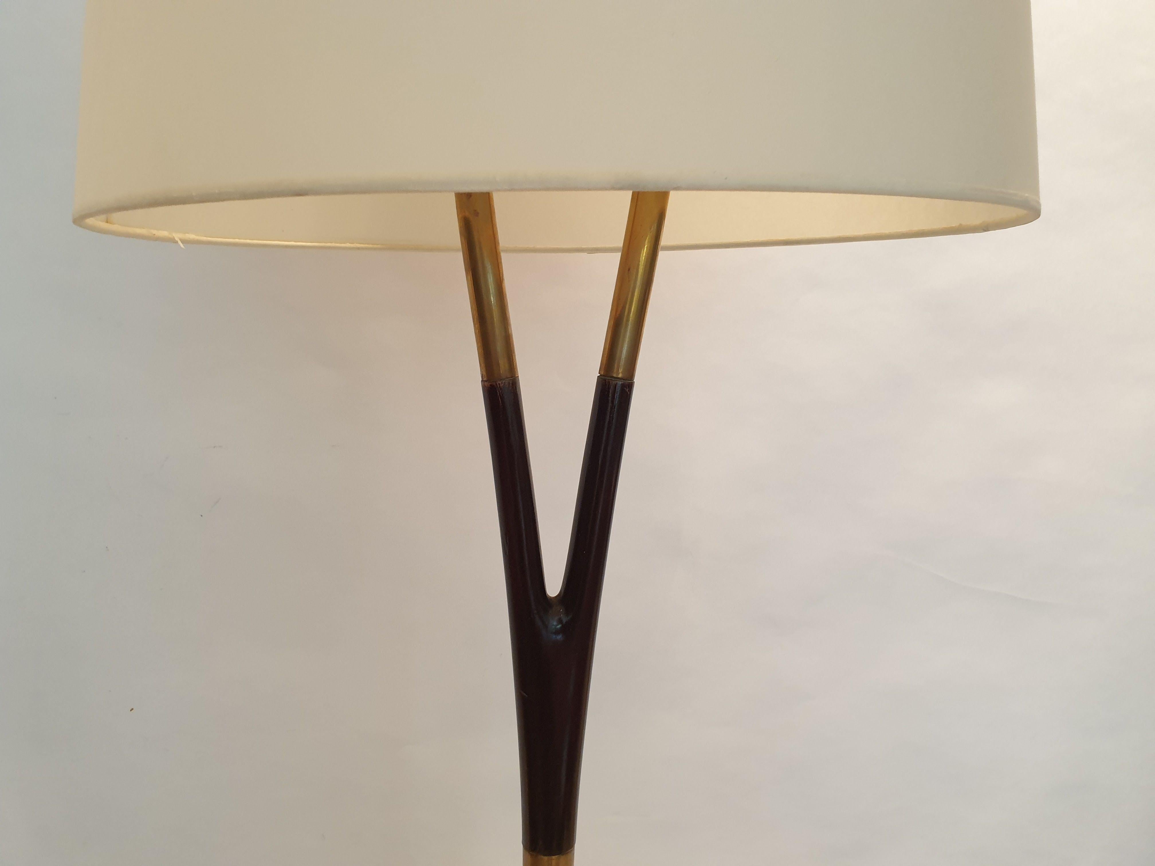 Floor lamp with polished wood stem with brass banding, sitting on a white marble base.