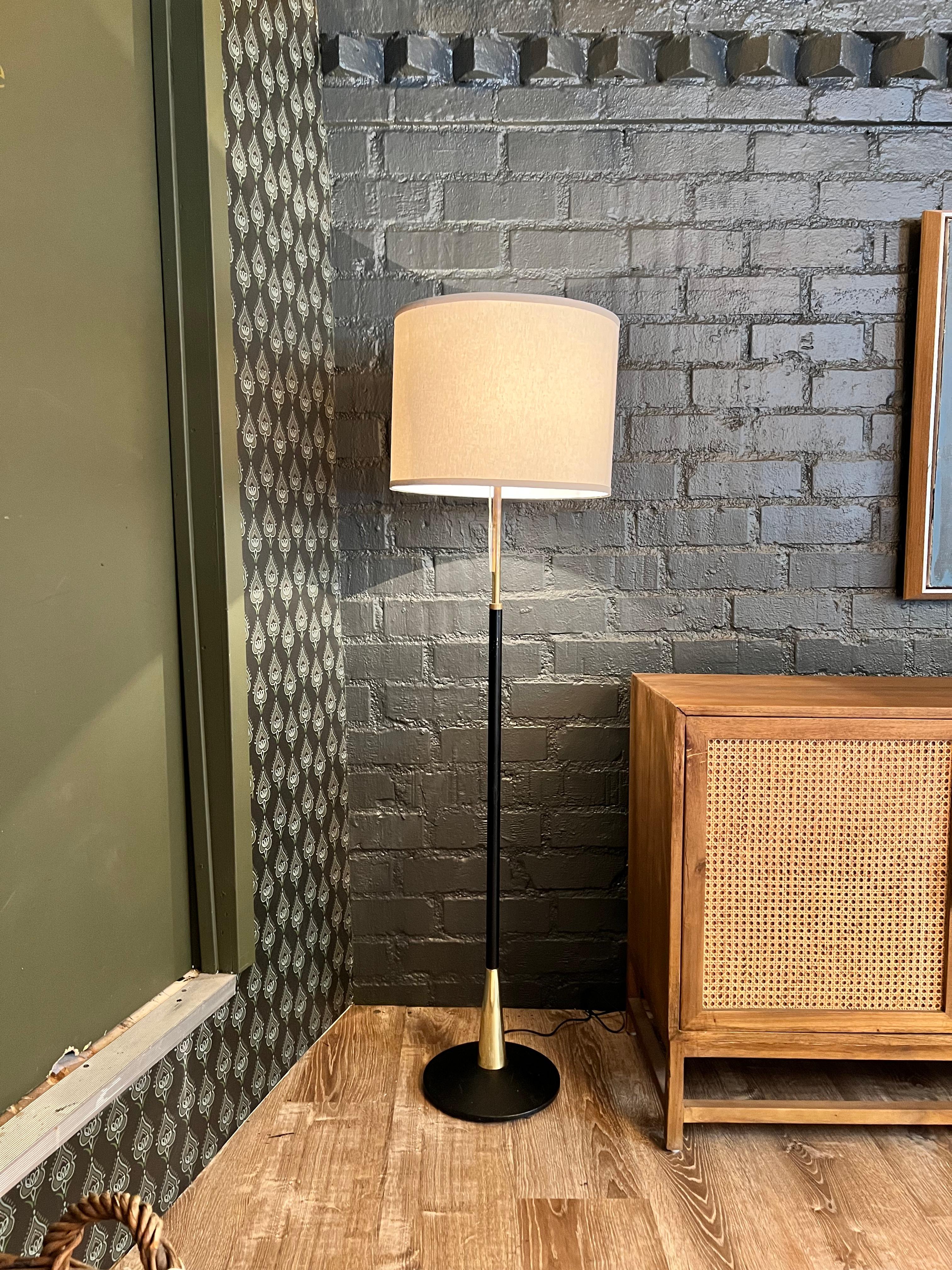 Vintage floor lamp with a fabric shade. The stand is constructed in black and gold metal. The color of the fabric shade has a cream-like color. Its minimal aesthetic is suitable for any interior. 