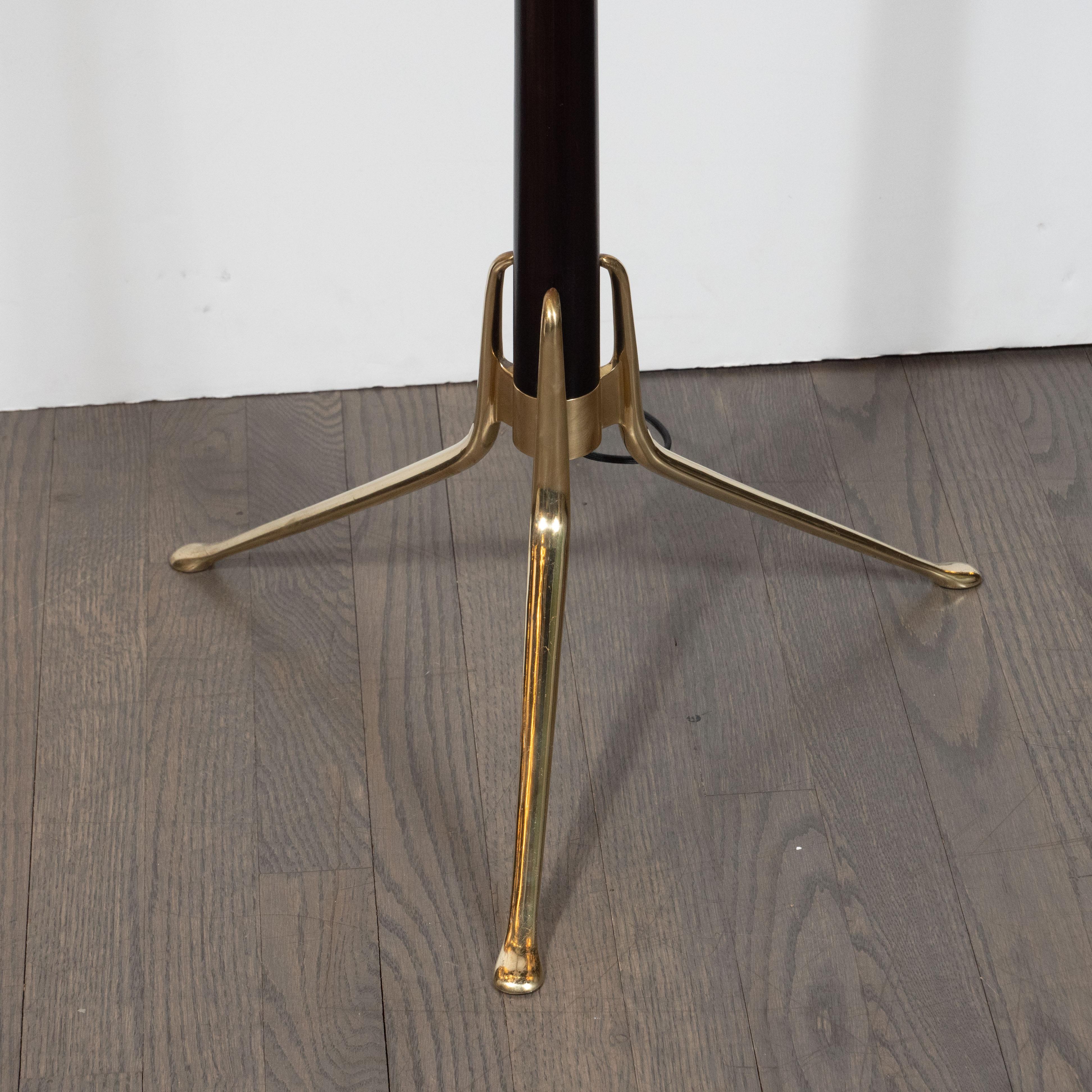 This stunning and sculptural Mid-Century Modern floor lamp was realized by the esteemed designer, Gerald Thurston, in the United States, circa 1950. It features sculptural brass legs that extend from the ebonized body of the fixture at an angle