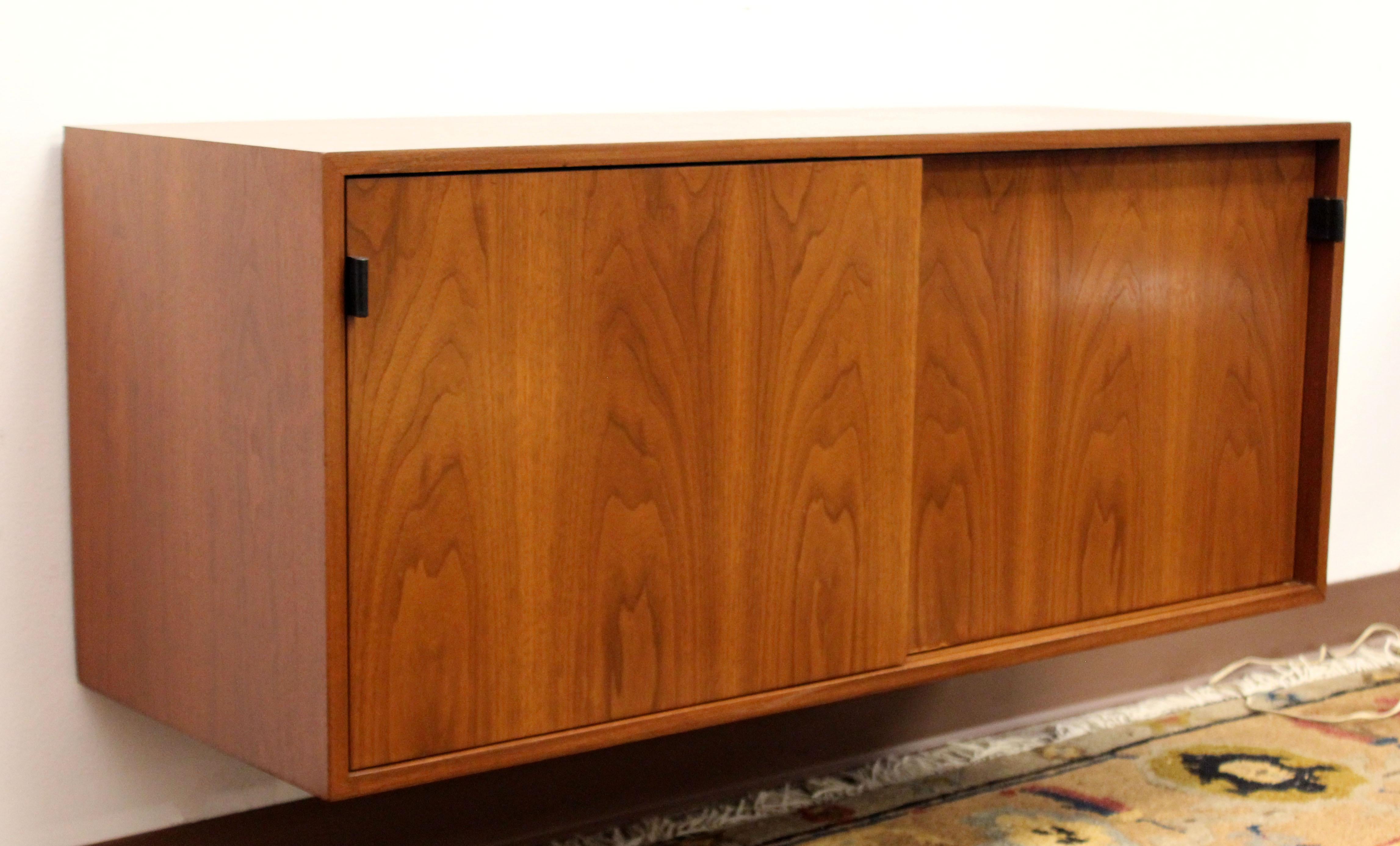 For your consideration is a fabulous rare vintage hanging floating wall unit cabinet, with sliding doors, made of walnut, by Florence Knoll, circa the 1960s. In excellent condition. The dimensions are 48