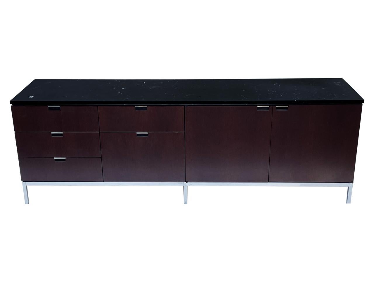A sleek modern classic cabinet designed by Florence Knoll and produced by Knoll. It features a dark mahogany case, stainless steel legs and a black marble top.