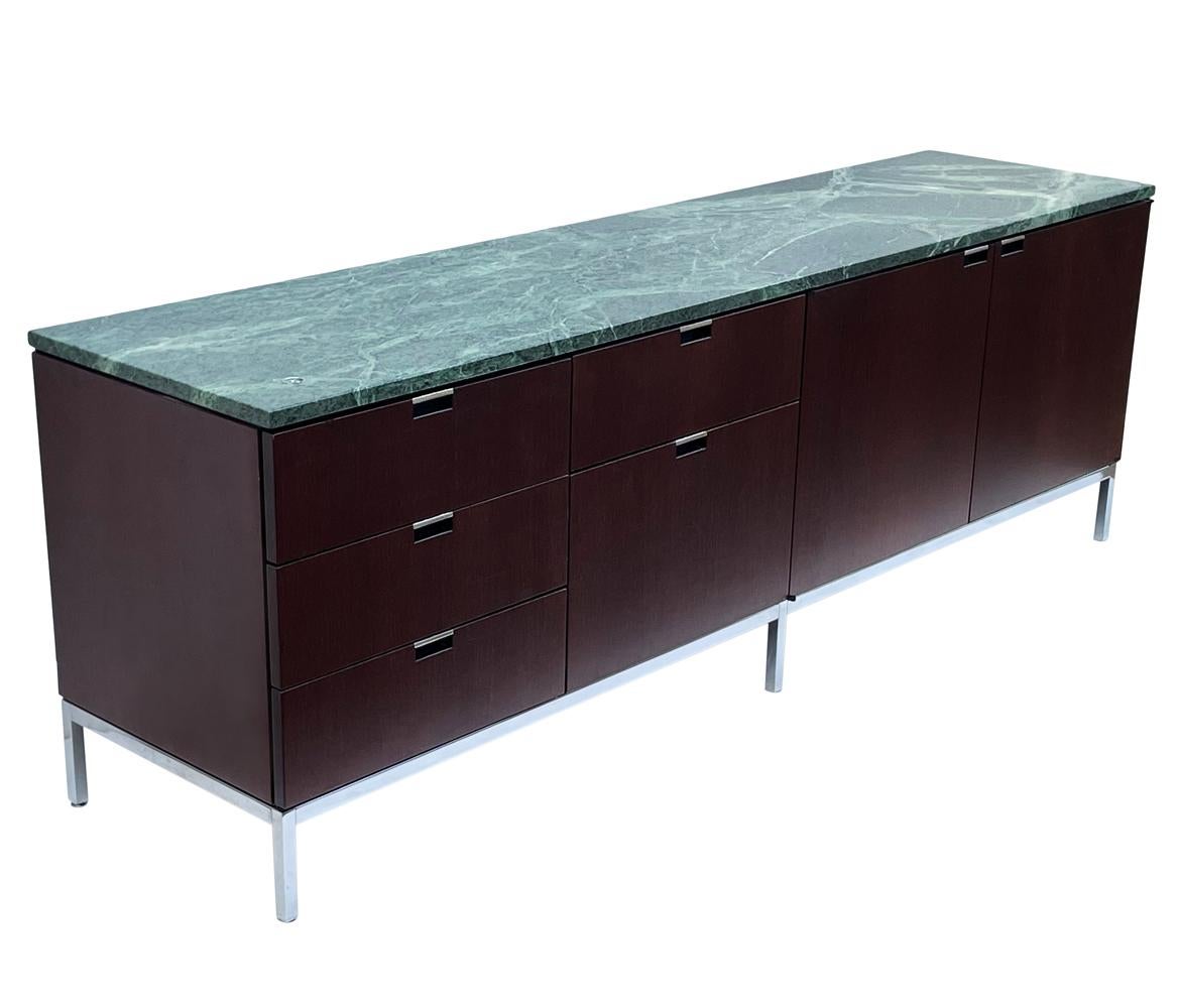 A sleek modern classic cabinet designed by Florence Knoll and produced by Knoll. It features a dark mahogany case, stainless steel legs and a rare green marble top. This has a drawer and cabinet configuration with tons of storage.