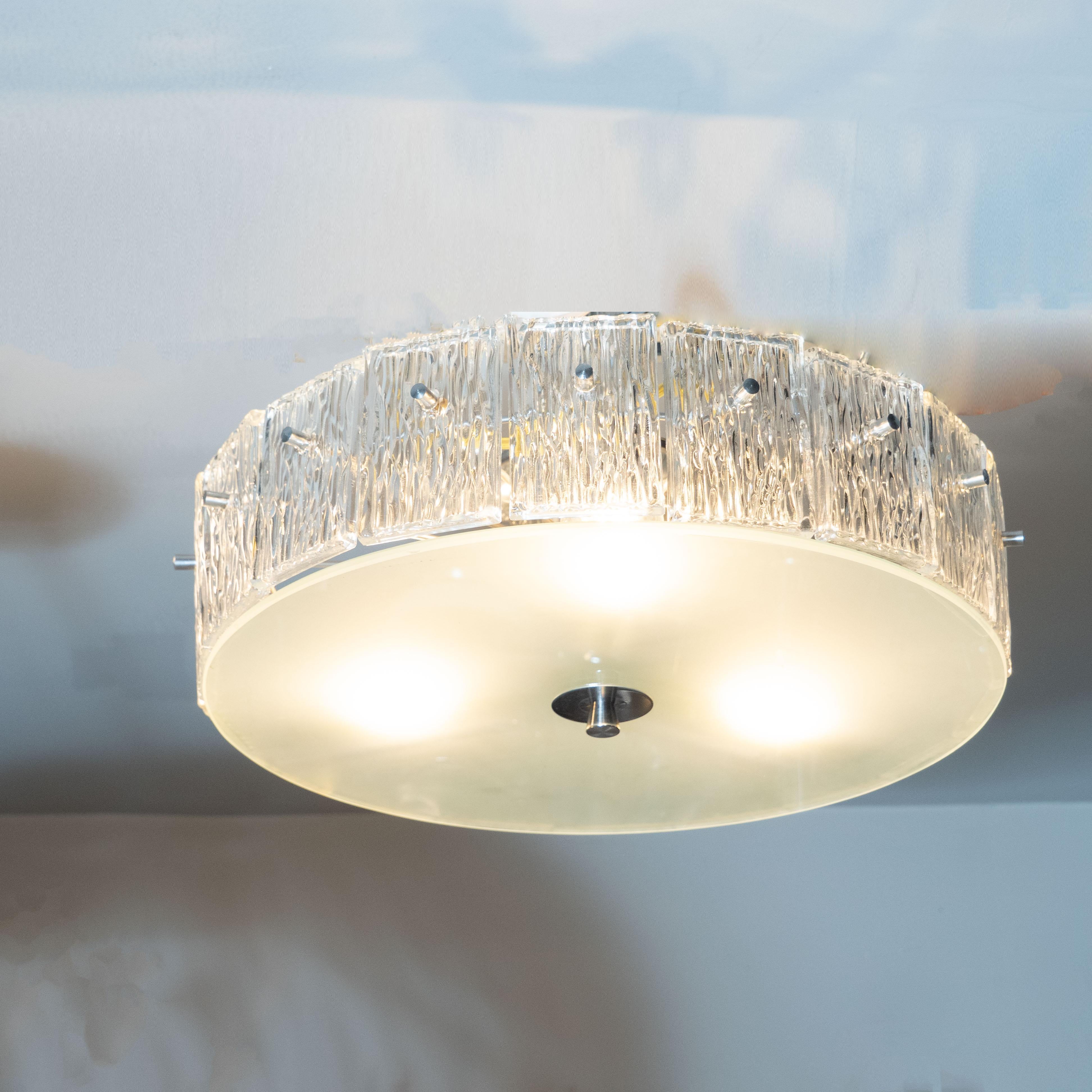 This elegant Mid-Century Modern chandelier was realized by the esteemed Mid-Century Modern maker, Kinkeldey, in Germany, circa 1960. It features a volumetric circular body with an abundance of rectangular glass shades- each with an organic texture