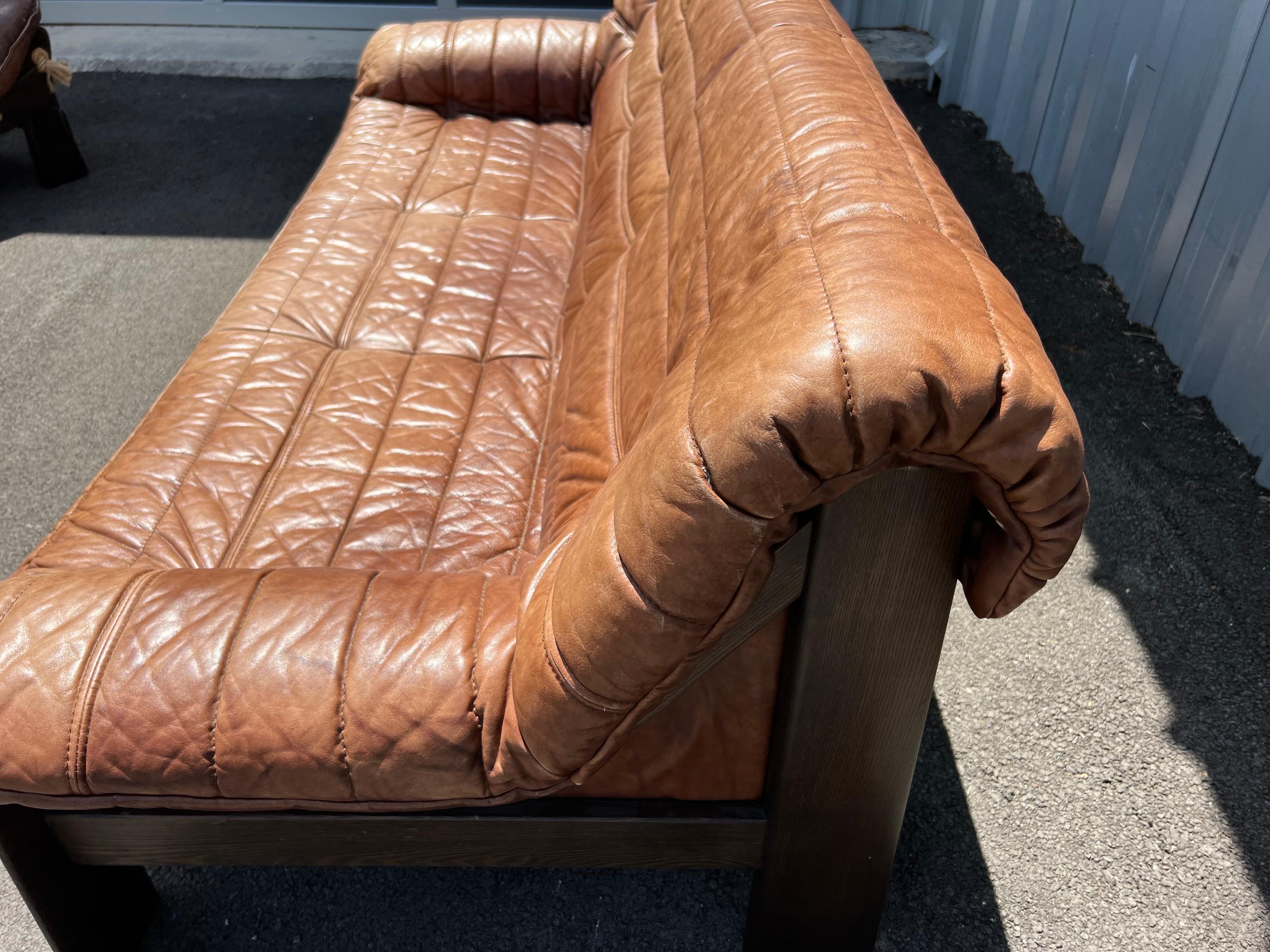 Mid-Century Modern fluted leather sofa in a warm brown color that sits on a stained oak frame. This 3-seater is in great vintage condition. The maker is unknown.