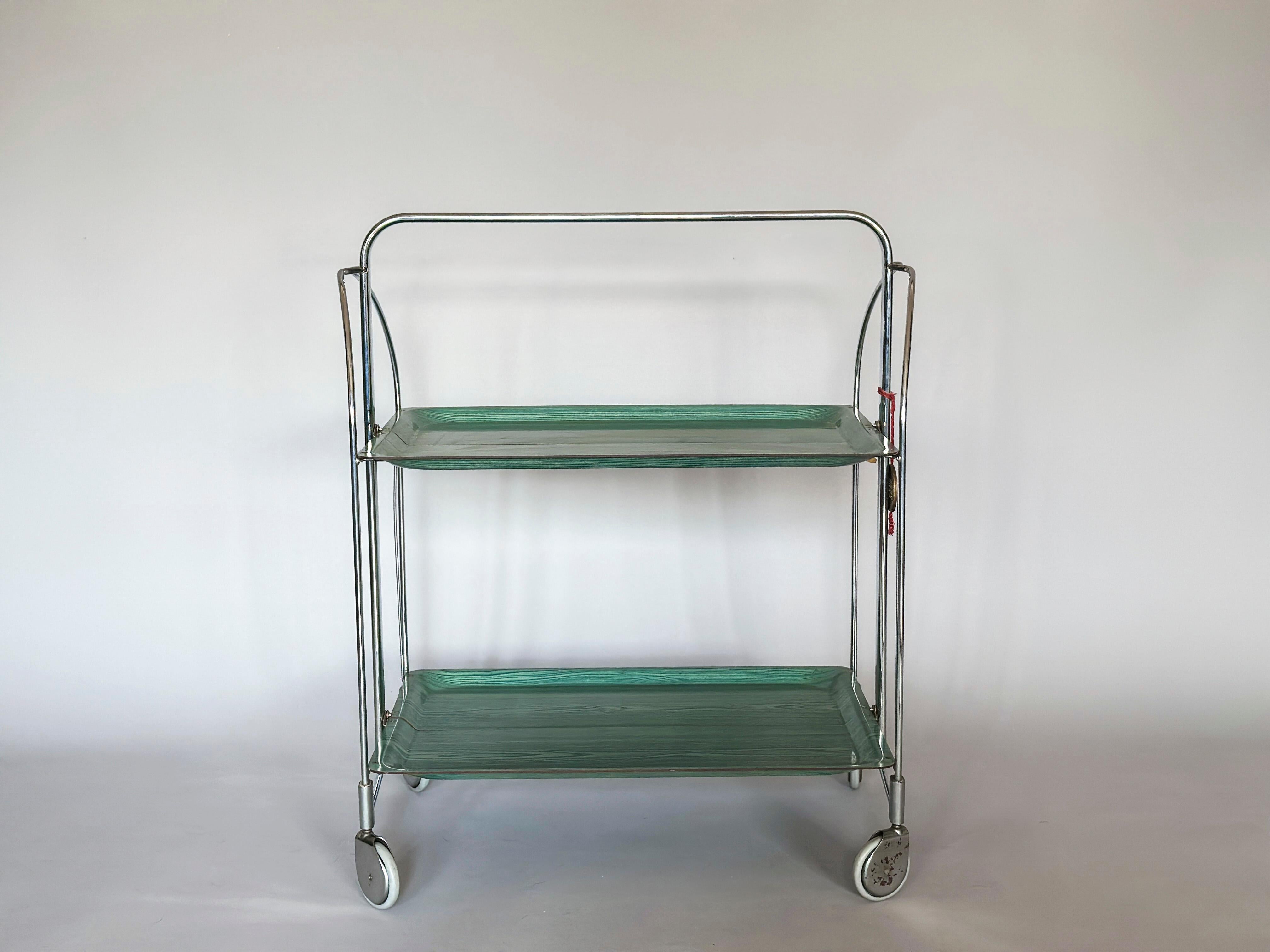 Mid-Century Modern folding bar cart on wheels from Gerlinol from circa 1960. 

The trolley folds out on one side.