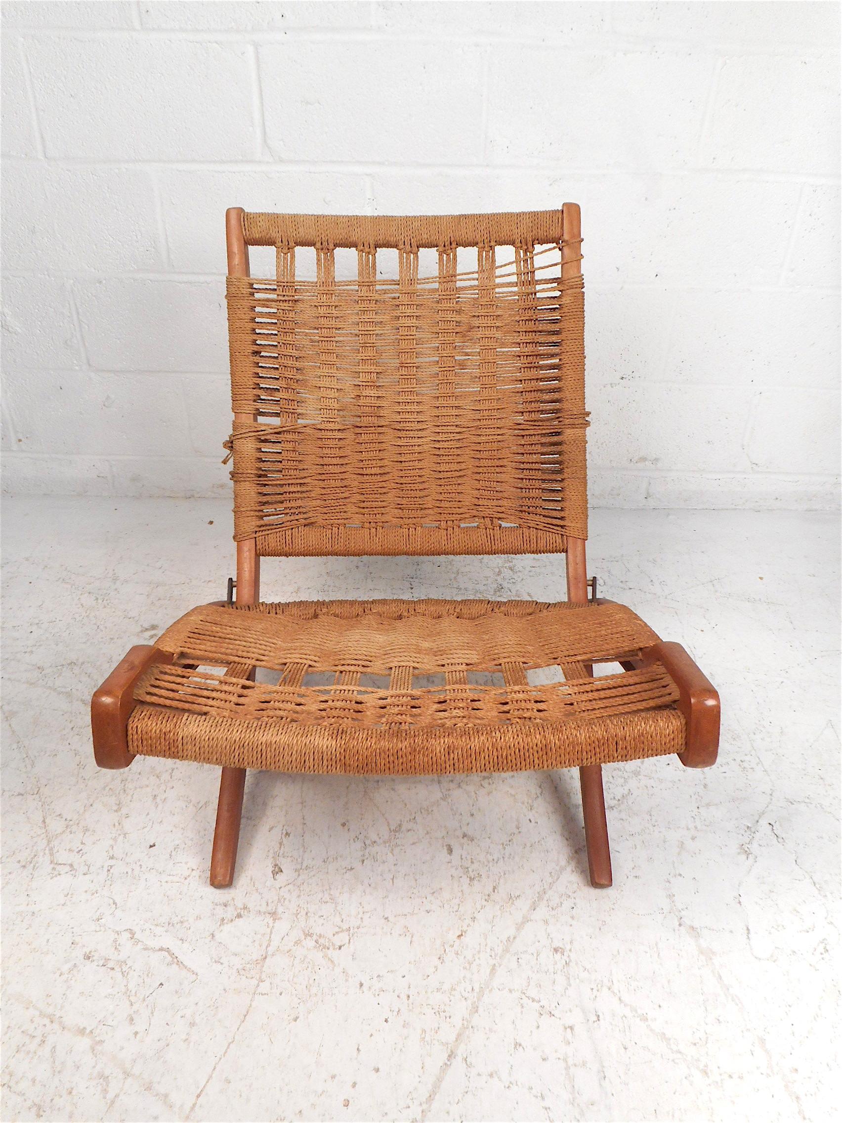 Stylish Mid-Century Modern folding chair in the style of Hans Wegner. Interestingly contoured wooden frame with a hinge which allows the chair to fold up easily when not in use. Comfortable and visually appealing woven rope upholstery on the seat
