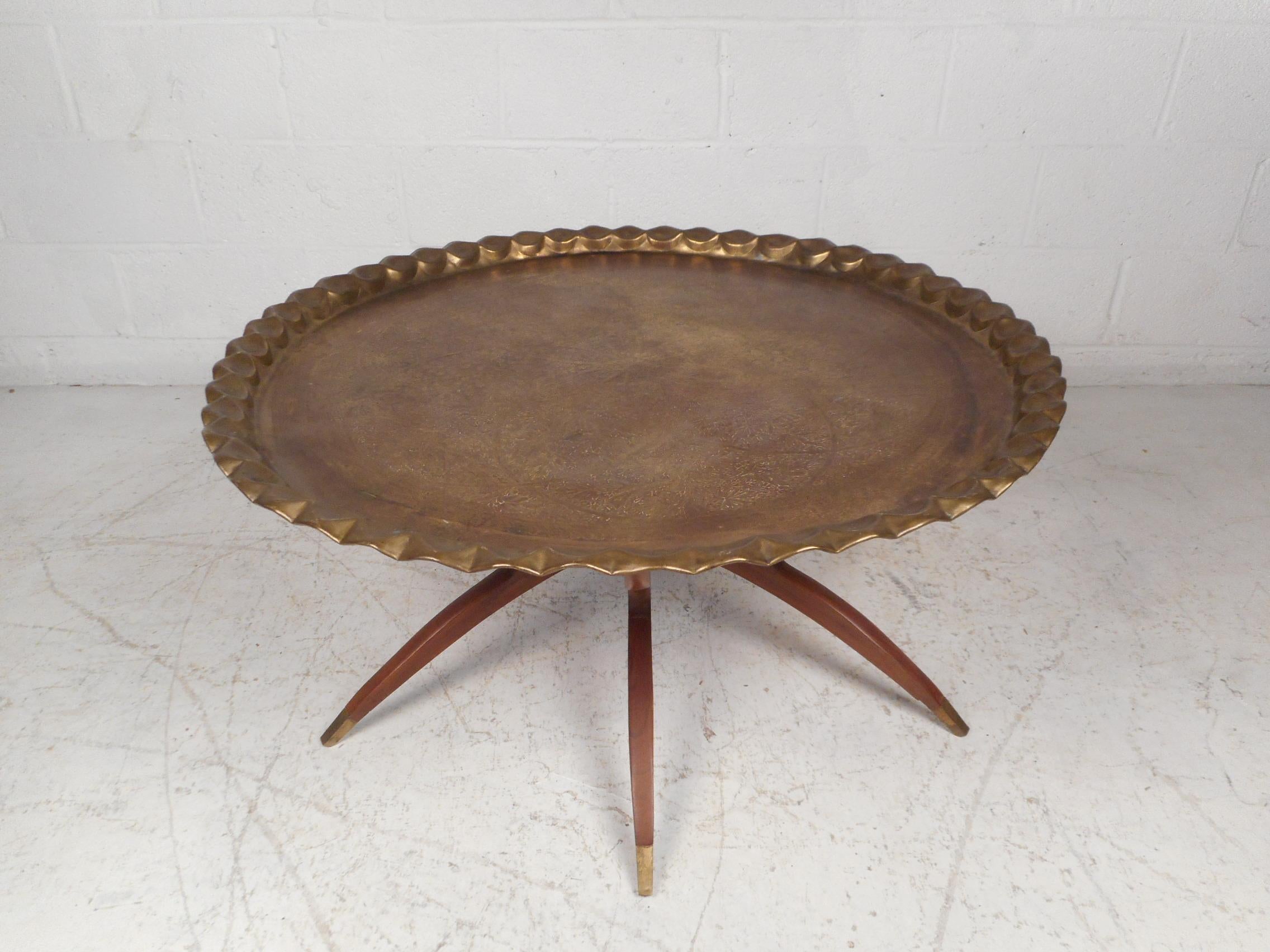 Very unusual midcentury cocktail table with a collapsing/folding base, and a large brass tabletop. Each wooden section of the base showcases an interesting sculpted profile with brass sabots at their feet, offering a nice continuity throughout the