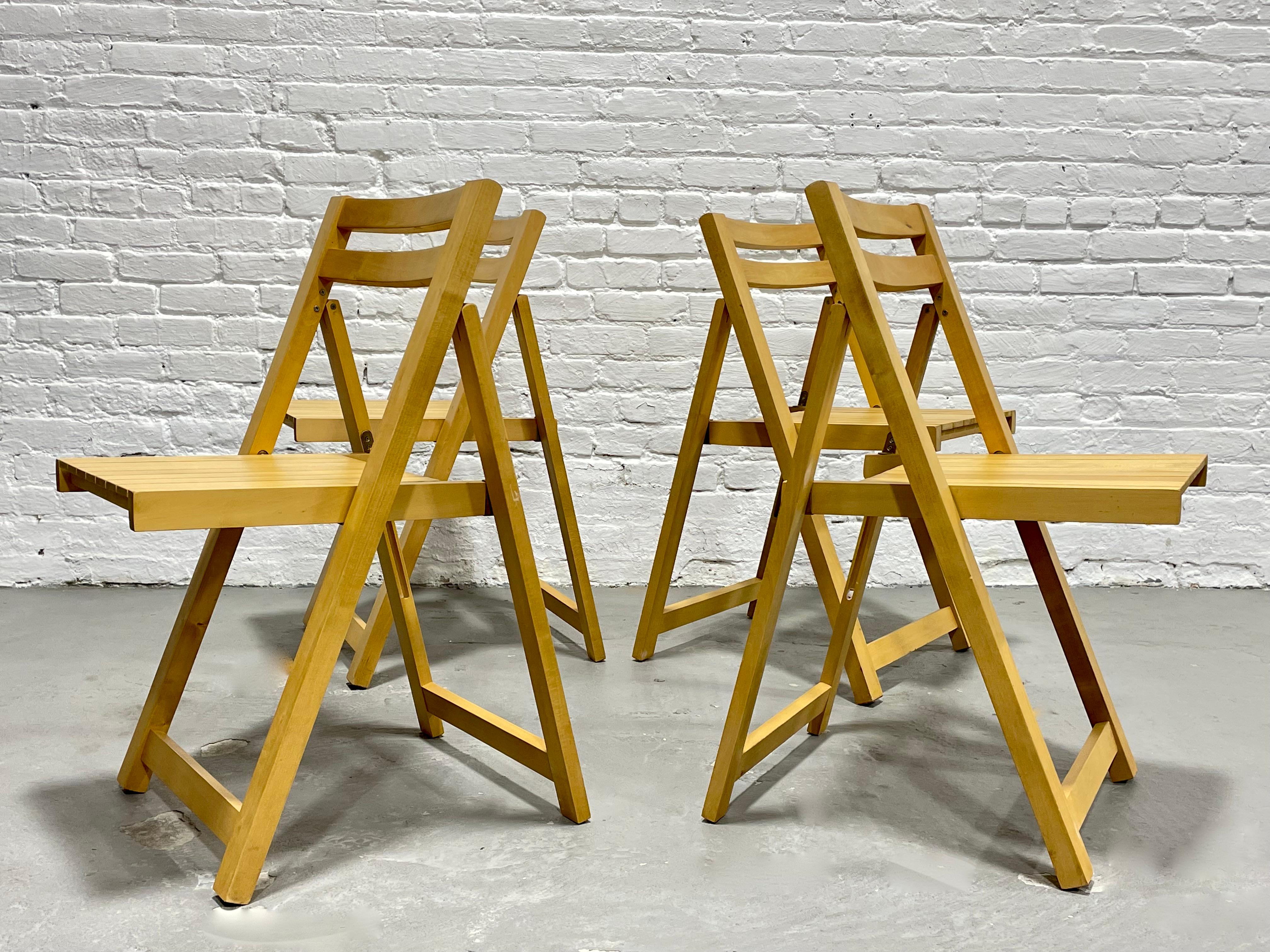 Mid Century Modern set of four solid beech folding chairs, made in Romania. This solid and sturdy set offers minimalist lines and looks amazing from every angle. The chairs fold completely flat for storage. Use these as your everyday set or store