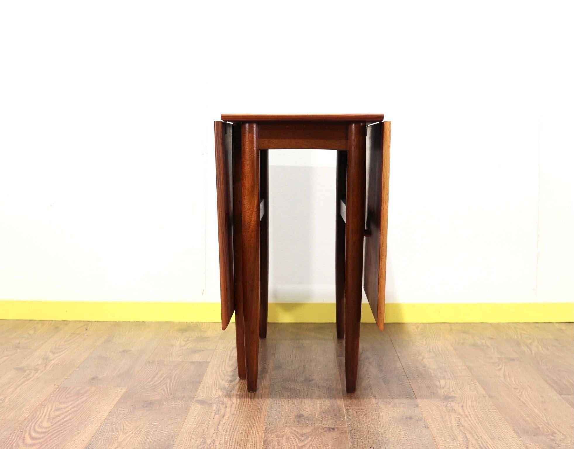 A beautiful mid century folding gate leg table by British furniture maker Morris of Glasgow. A gorgeous grain gives this table a stunning look. It can fit into tight spaces when not needed and then folded out with either one or two flaps extended