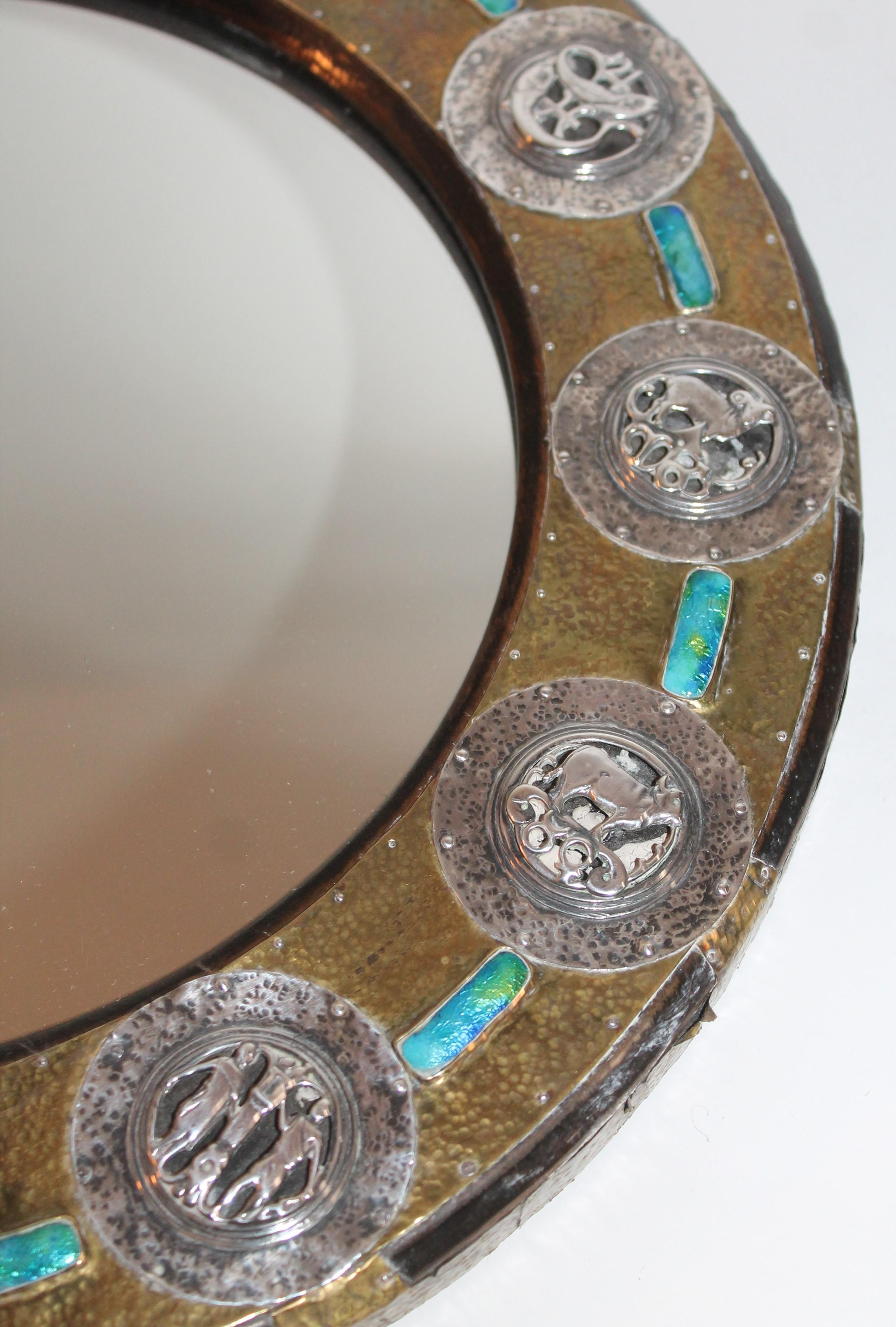 This Mid-Century Modern artists created this enameled on brass and sterling silver zodiac symbols. This is a one of a kind mirror as well. The frame is a heavy wood base.