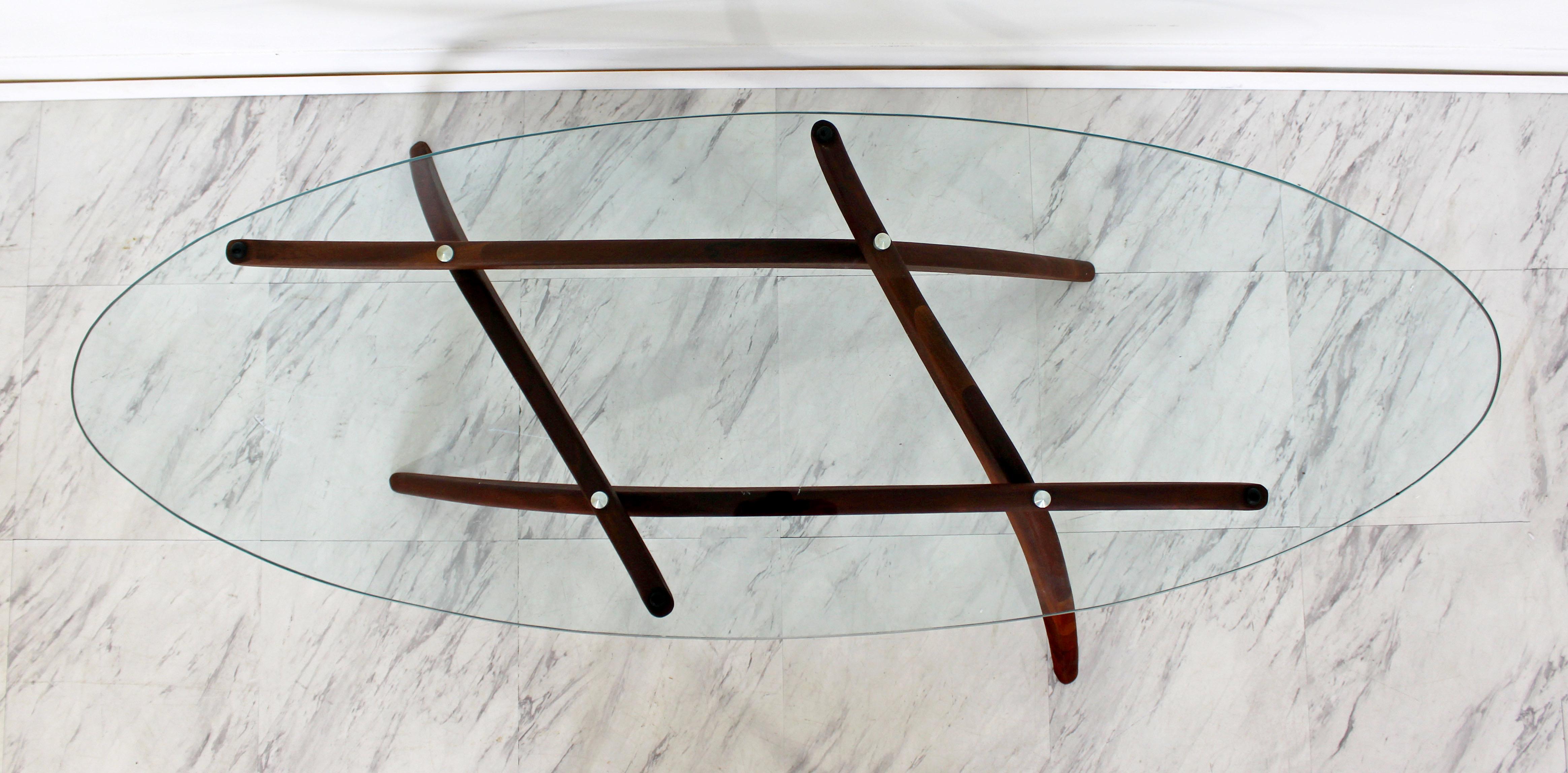 For your consideration is a wonderful coffee table, with a sculptural walnut base and oval glass top, by Forest Wilson, circa the 1960s. Often mistakenly identified as Adrian Pearsall. In very good condition. The dimensions are 53