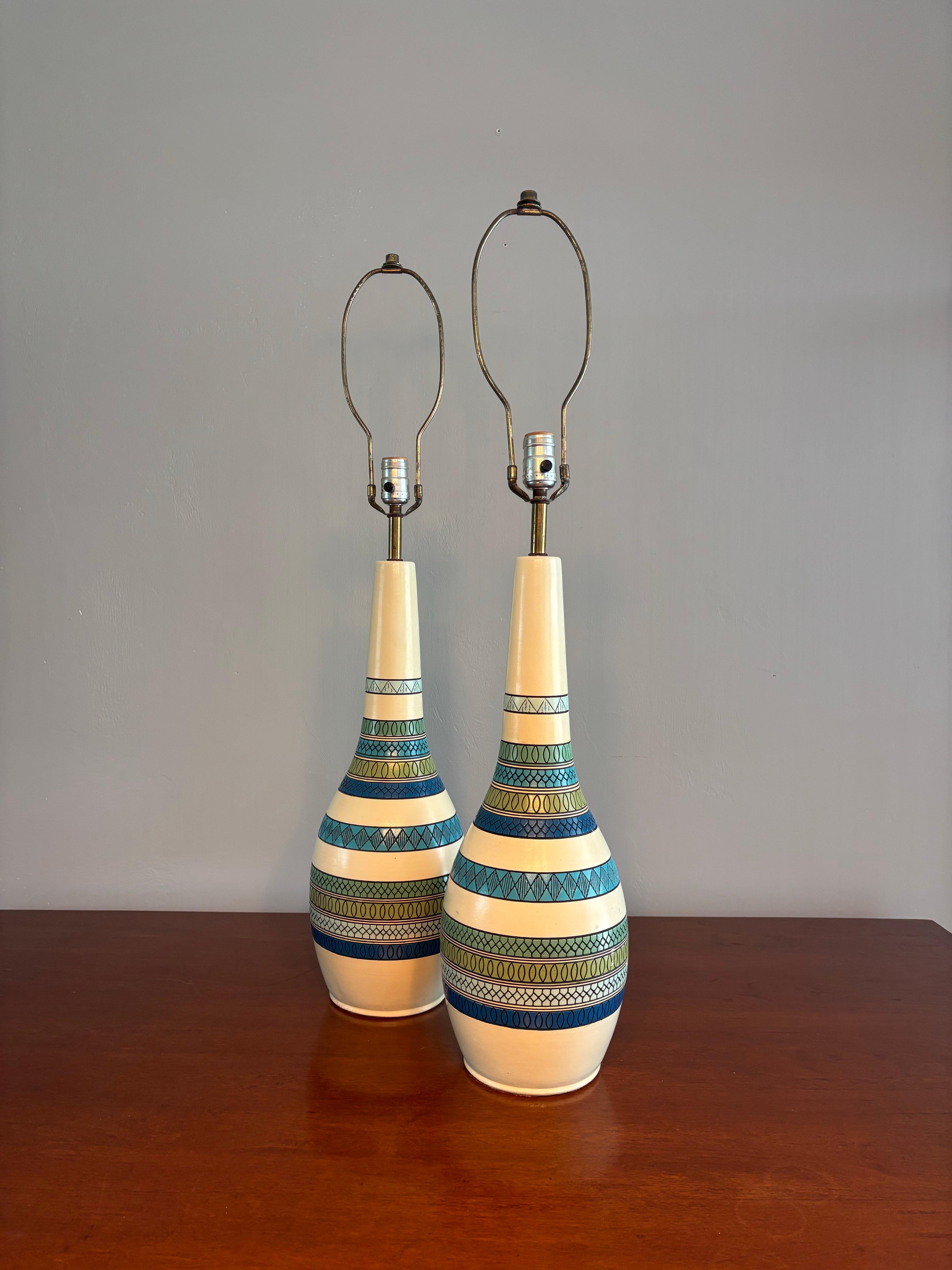 Preciosa pareja de lámparas de sobremesa de la empresa Fortune Lamp. Forma y color clásicos de la modernidad de mediados de siglo. Vaso alargado de cerámica con un fino tallo acanalado. Detalles de rayas azules y verdes. 

Fabricado en 1961.