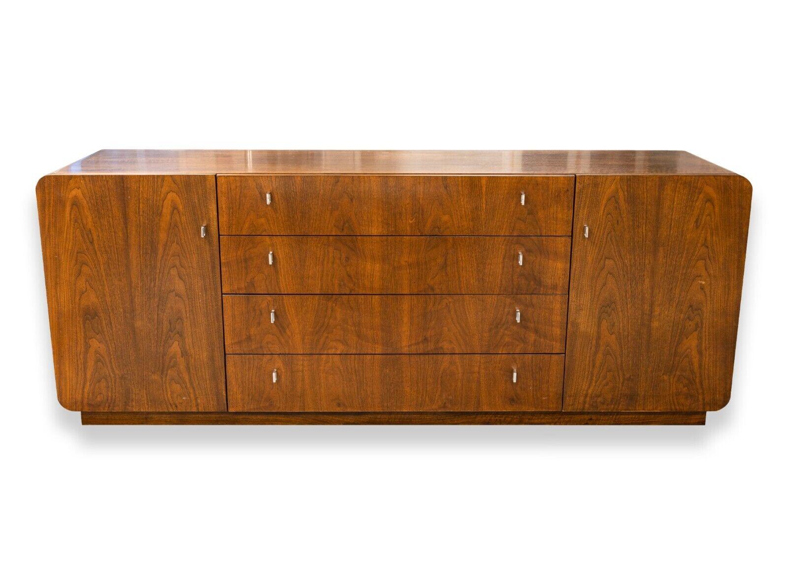 A mid century modern Founders walnut and chrome dresser credenza and mirror. An absolutely jaw dropping piece of furniture from Founders furniture. This piece features an all walnut wood construction with a variety of drawers, cupboards, and a large