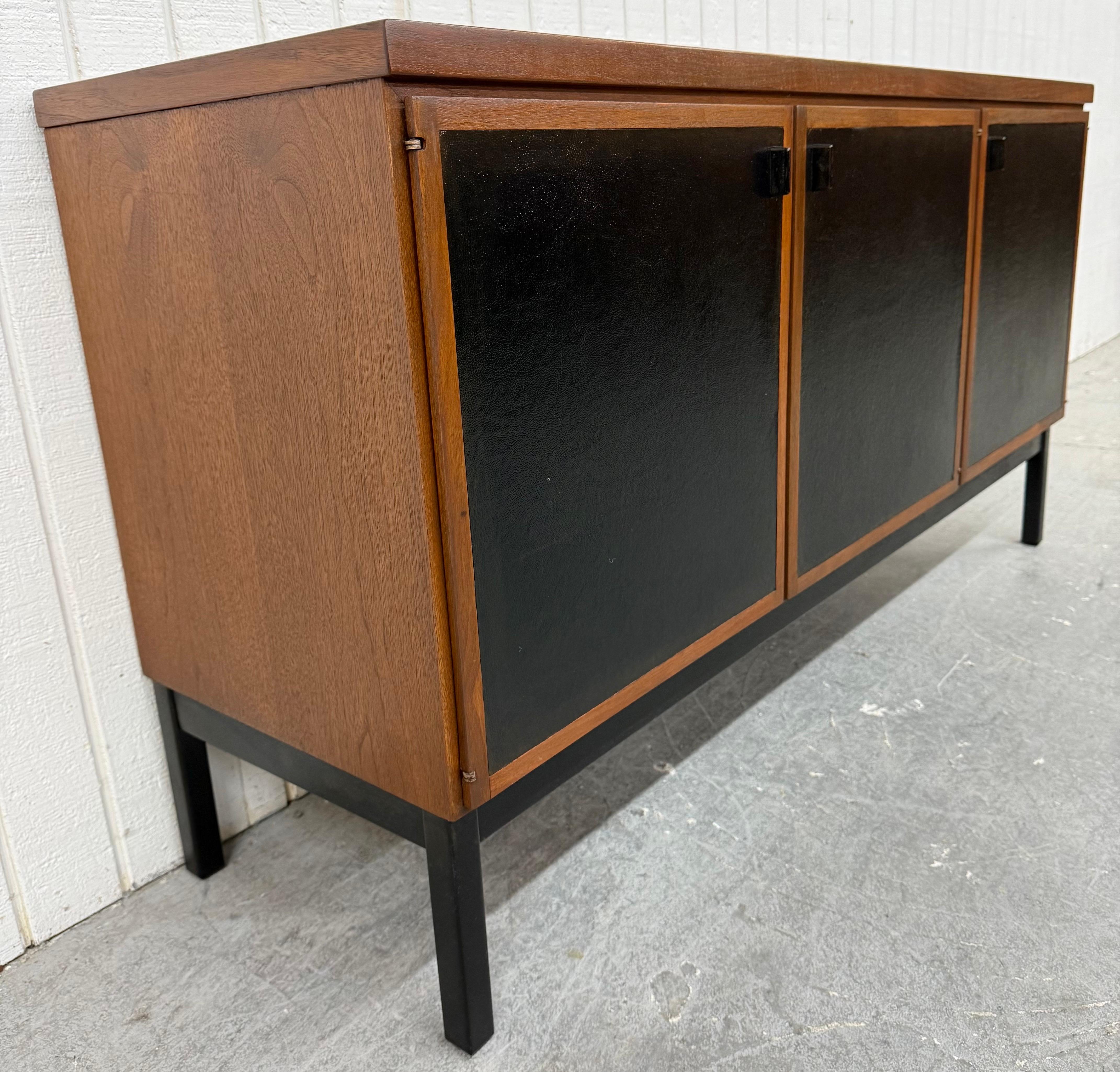 Questo annuncio si riferisce a una credenza in legno di noce Founders di epoca moderna. Caratterizzata da un design lineare, due ante a sinistra che si aprono per creare cassetti e spazio di archiviazione, una terza anta a destra con scaffali,