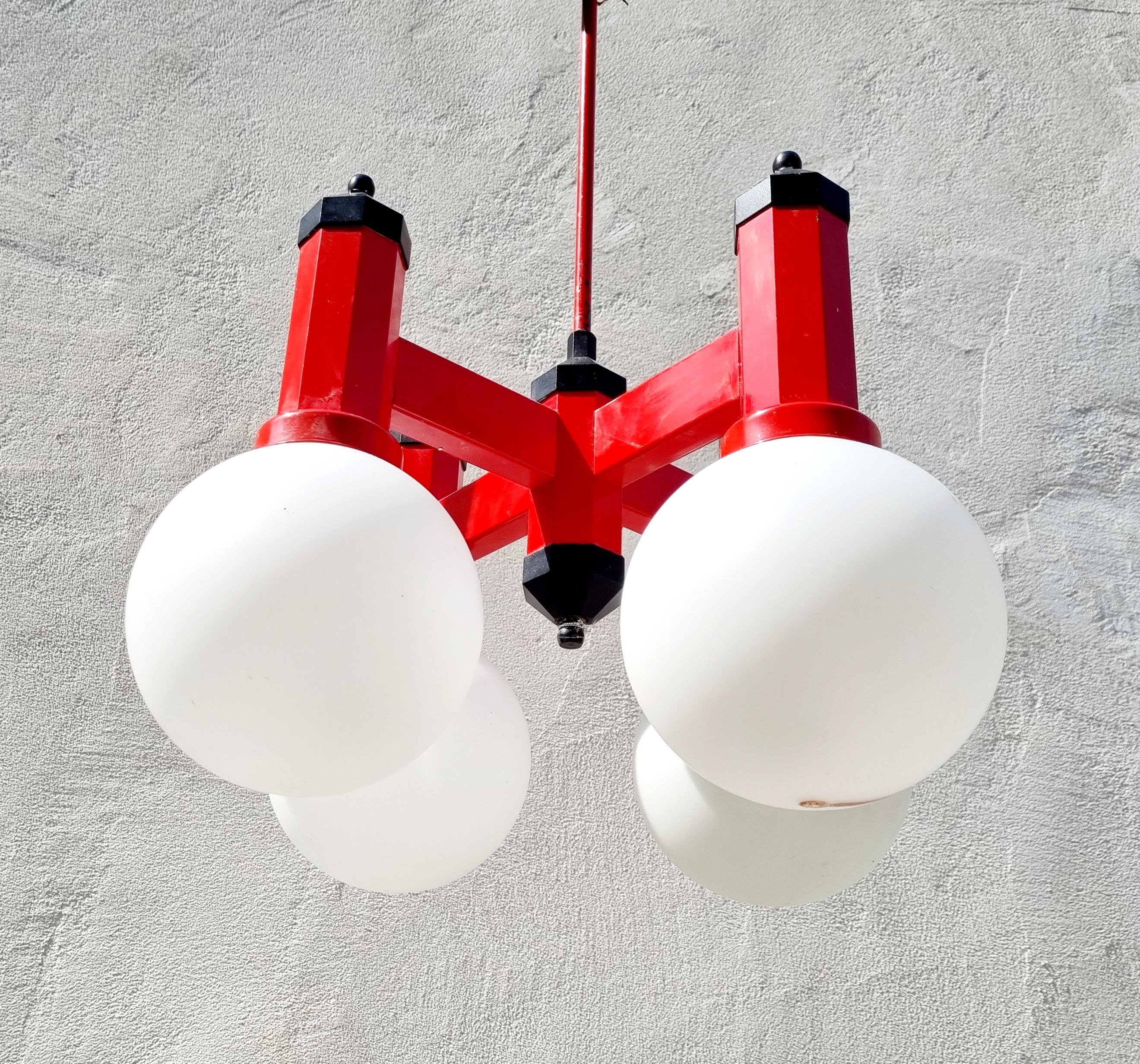 Mid Century Modern four arms Chandelier from '70s was made in Yugoslavia.
It is made of metal red base and four milk glass shades.
Lamp works perfectly. It is very unique and stylish. Very retro! 
Classice socialist design from the 70s