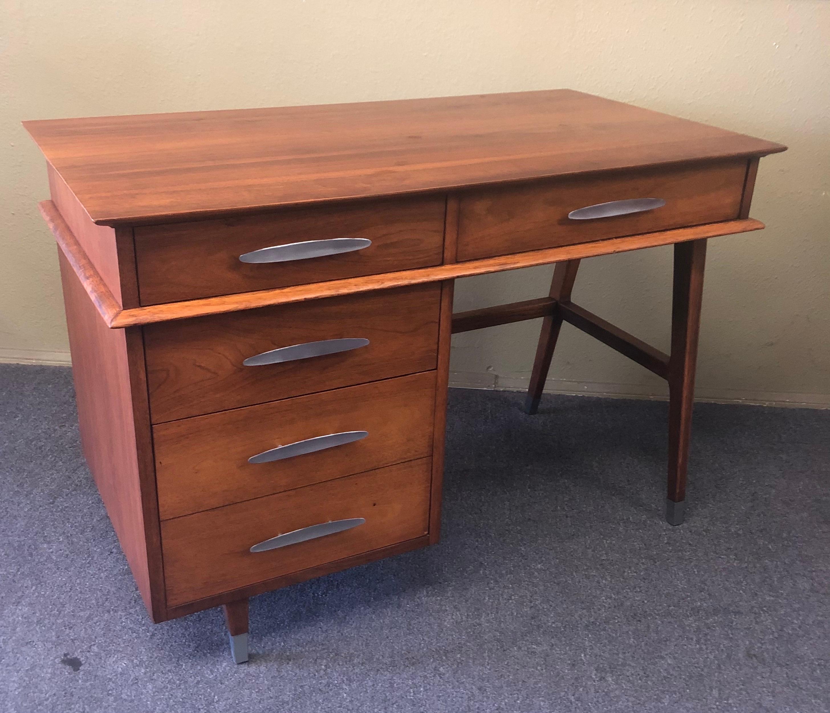 Mid-Century Modern four-drawer walnut writing desk with metal pulls and leg caps by Sligh-Lowry of Holland. MI, circa 1960s. The desk is finished on all sides and can be floated in the center of any room. The piece is in very good vintage condition