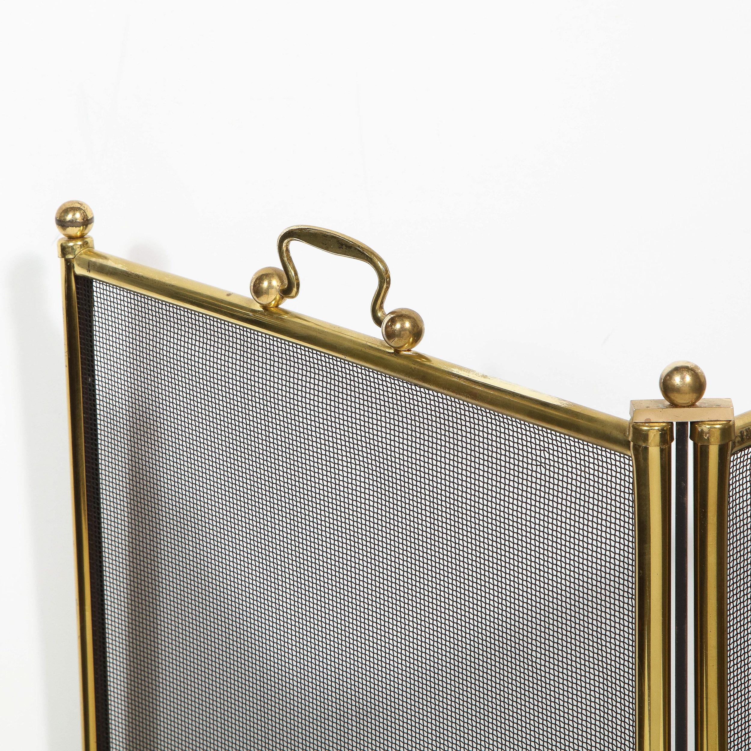 This elegant Mid-Century Modern four panel fire screen was realized in the United States, circa 1960. It features four panels with tubular brass perimeters and black mesh interiors. The joints connecting each of the panels are crowned with a