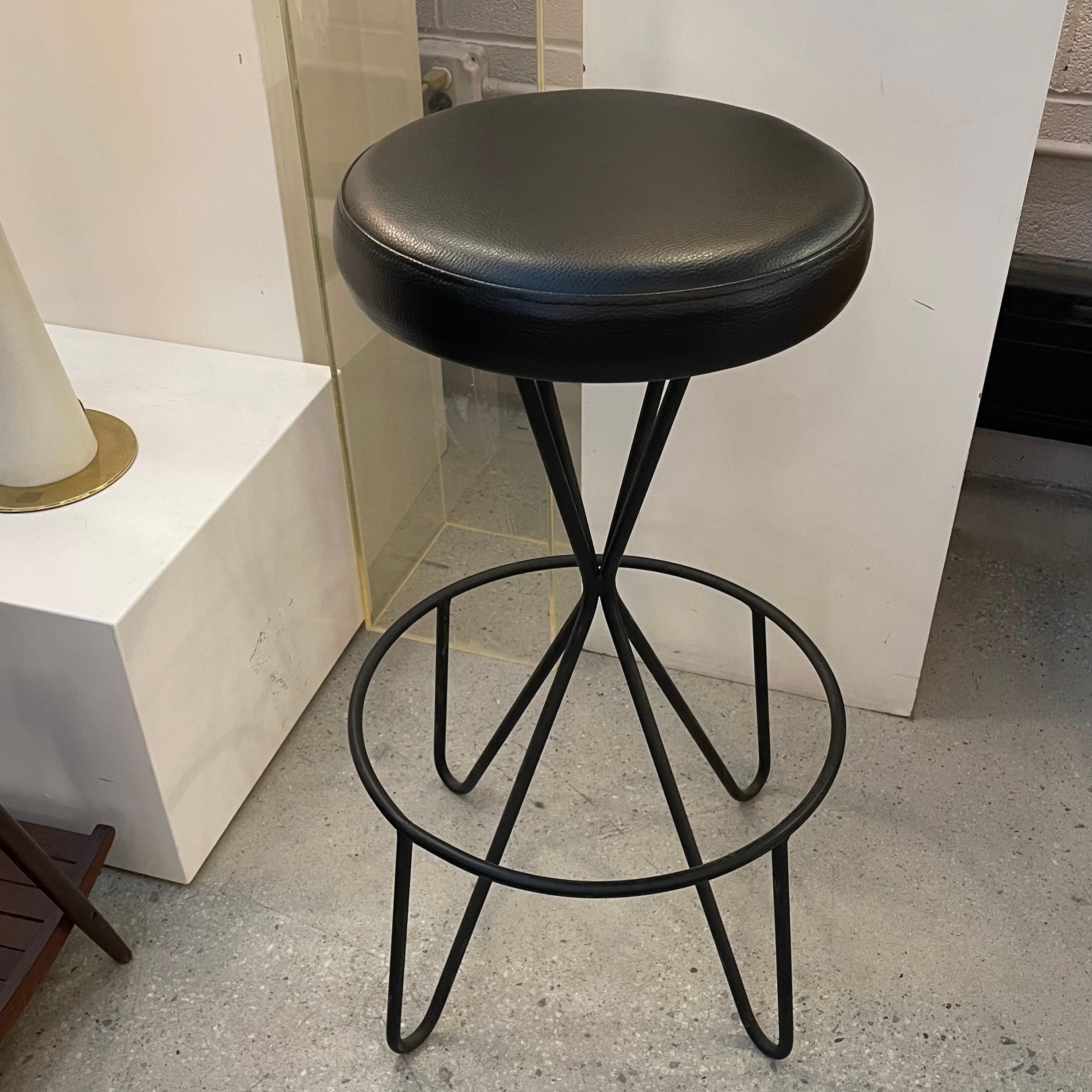 Mid-Century Modern, swivel bar stool by Frederick Weinberg with wrought iron base and re-upholstered black vinyl seat. The footrest is 17 inch diameter and the seat measures 14 inch diameter.