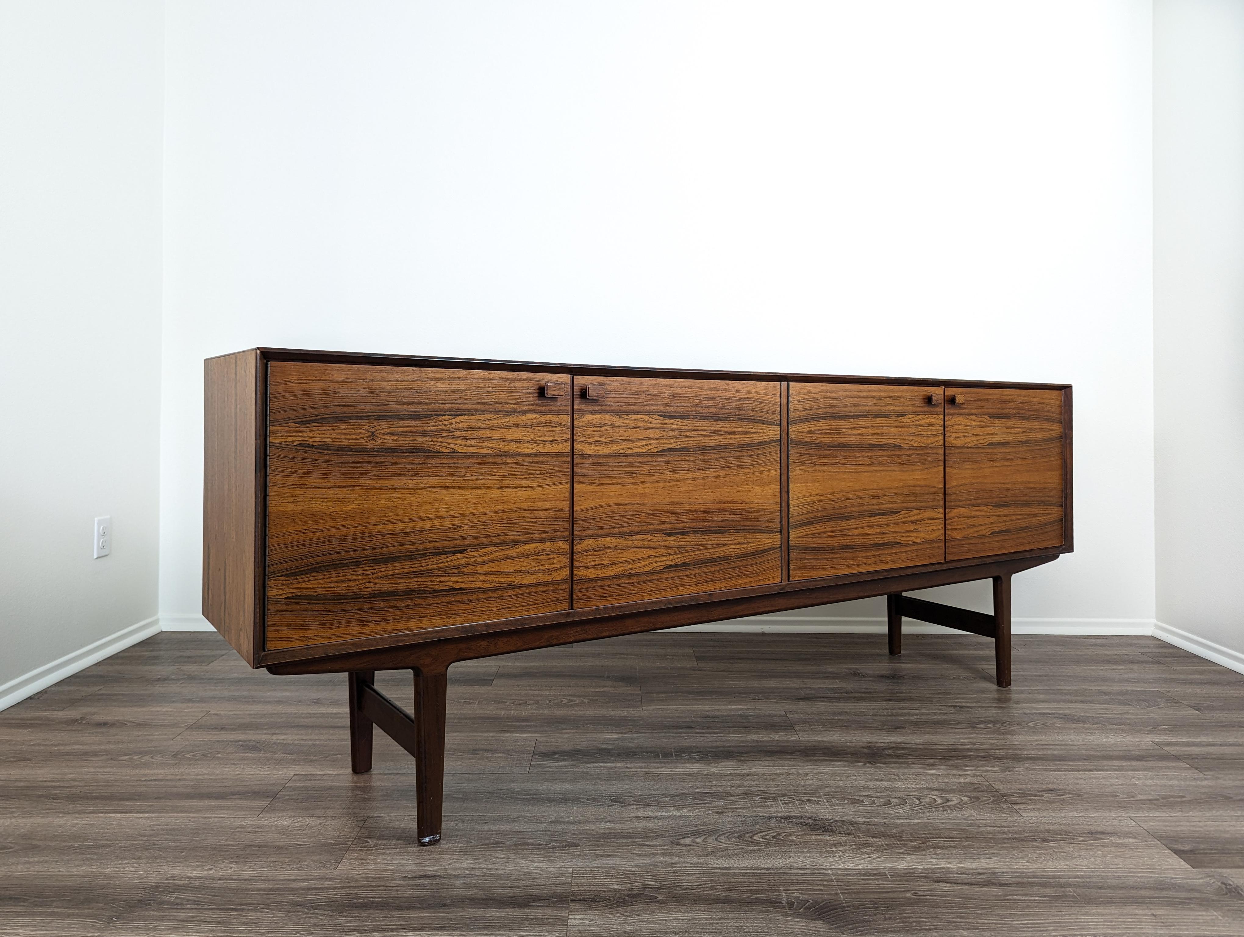 Delight in the flawless fusion of form and function with this exquisite Mid-Century Modern Rosewood Credenza designed by the legendary Fredrik Kayser. Crafted with meticulous precision, this stunning piece embodies the iconic minimalism and refined