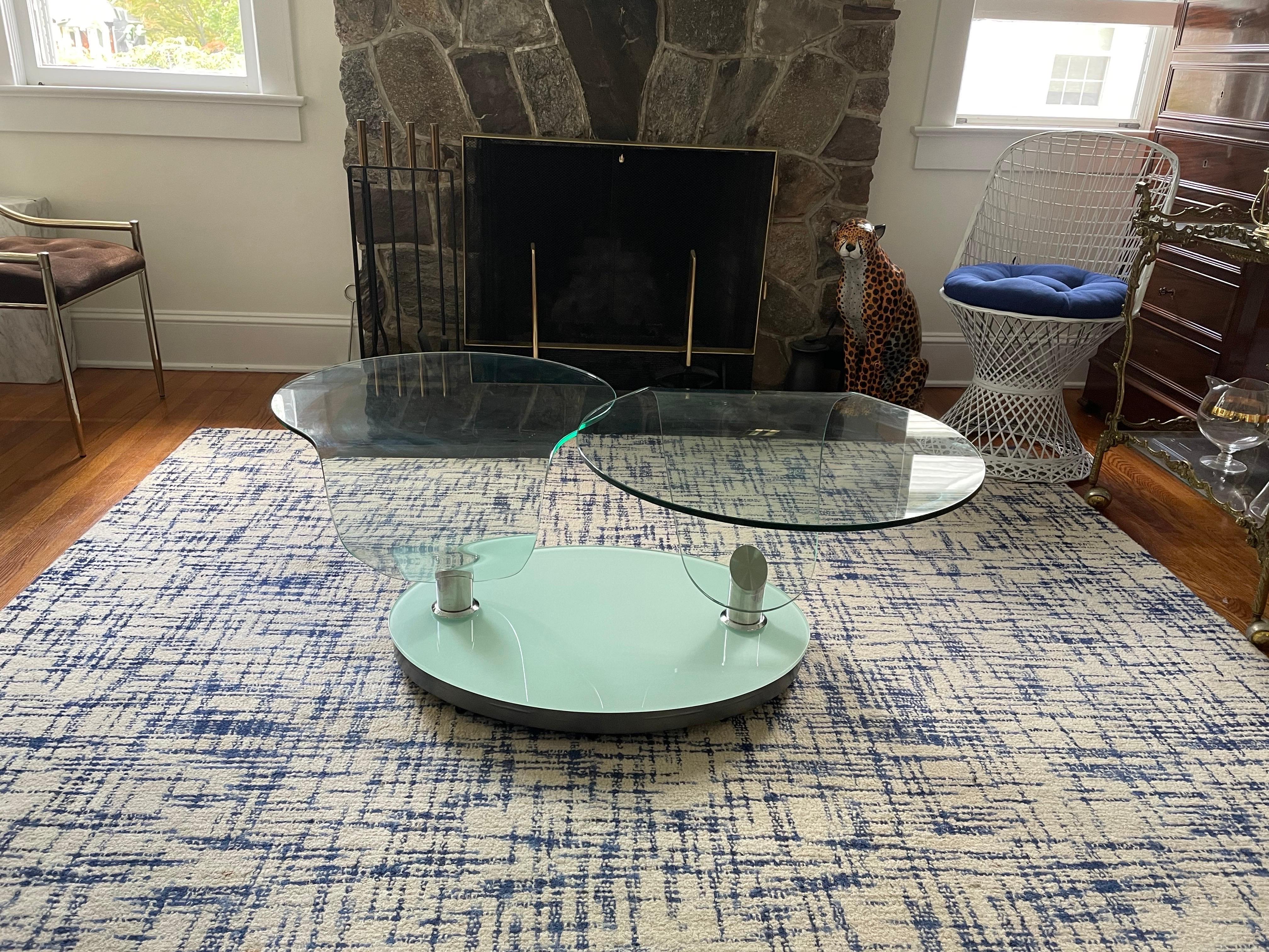 This stunning vintage modern coffee table features two free-form glass tops that swivel. Sleek design allows the width of the top to go from 34 inches wide to 63.25 inches wide. This beautiful table swivels inward saving plenty of space when it is