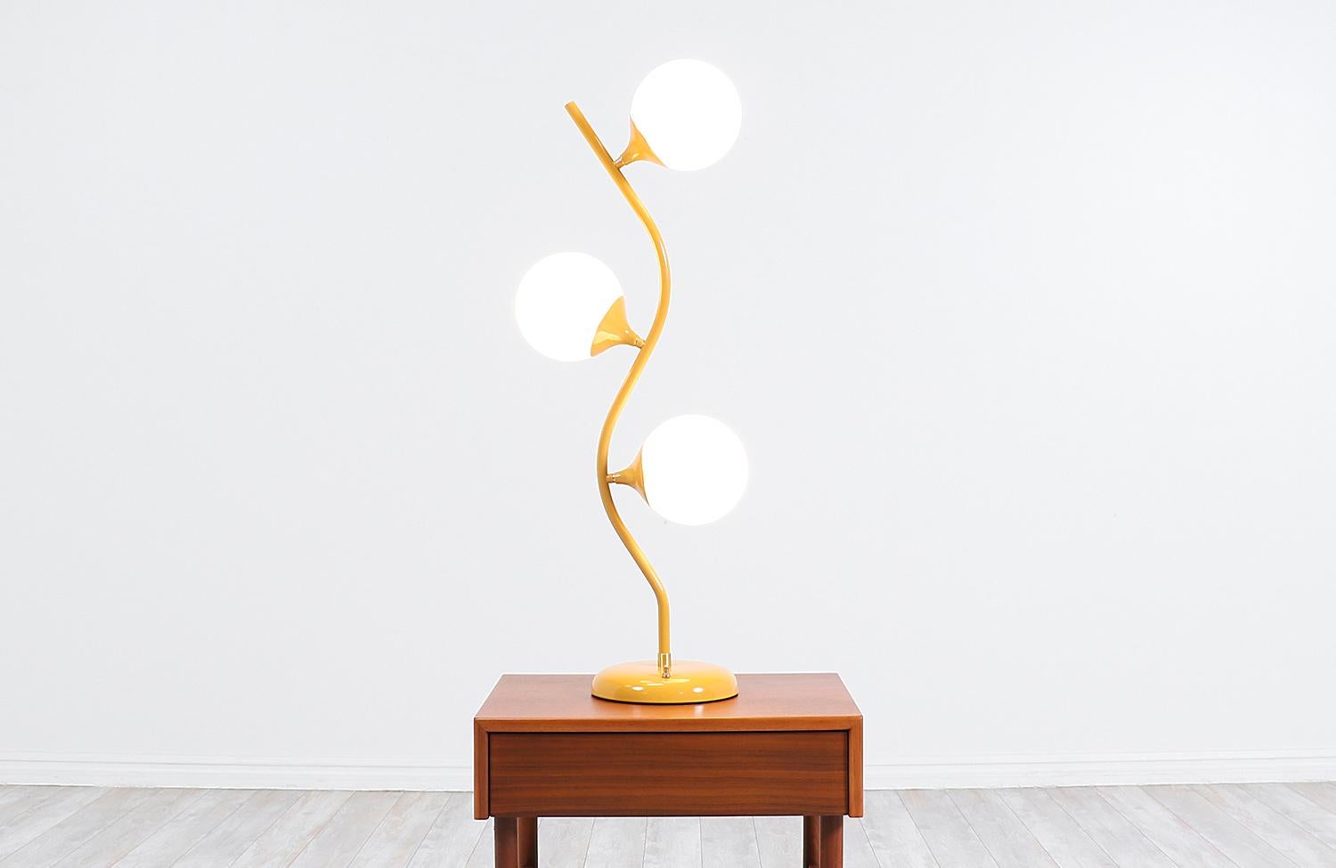 Vintage modern table lamp designed and made in the United States, circa 1960s. Our unique lamp features a mustard lacquered tulip base and stem that holds its glass globes that light up individually or together at the same time. Its organic and