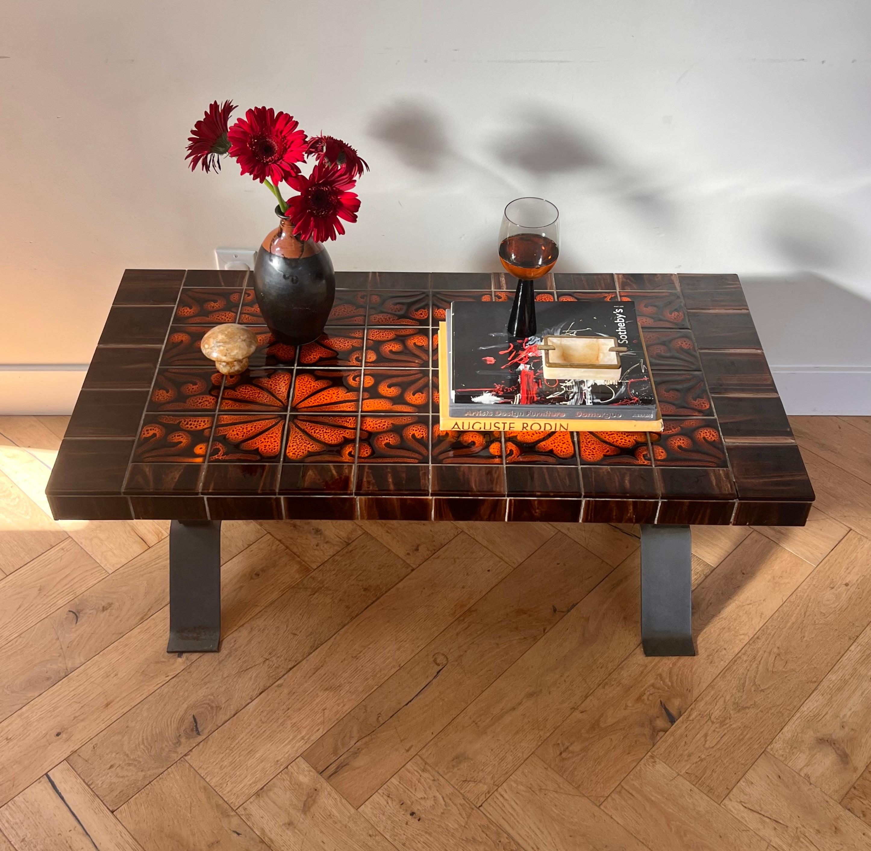 PSYCHÉ: a mid century modern French ceramic tiled and forged iron coffee table, late 1950s. Tones of blood orange, coral, and obsidian. Recalls the vibrant psychedelic patterns of Laplandian ryas.  Fabulous condition with minor signs of age. Pick up