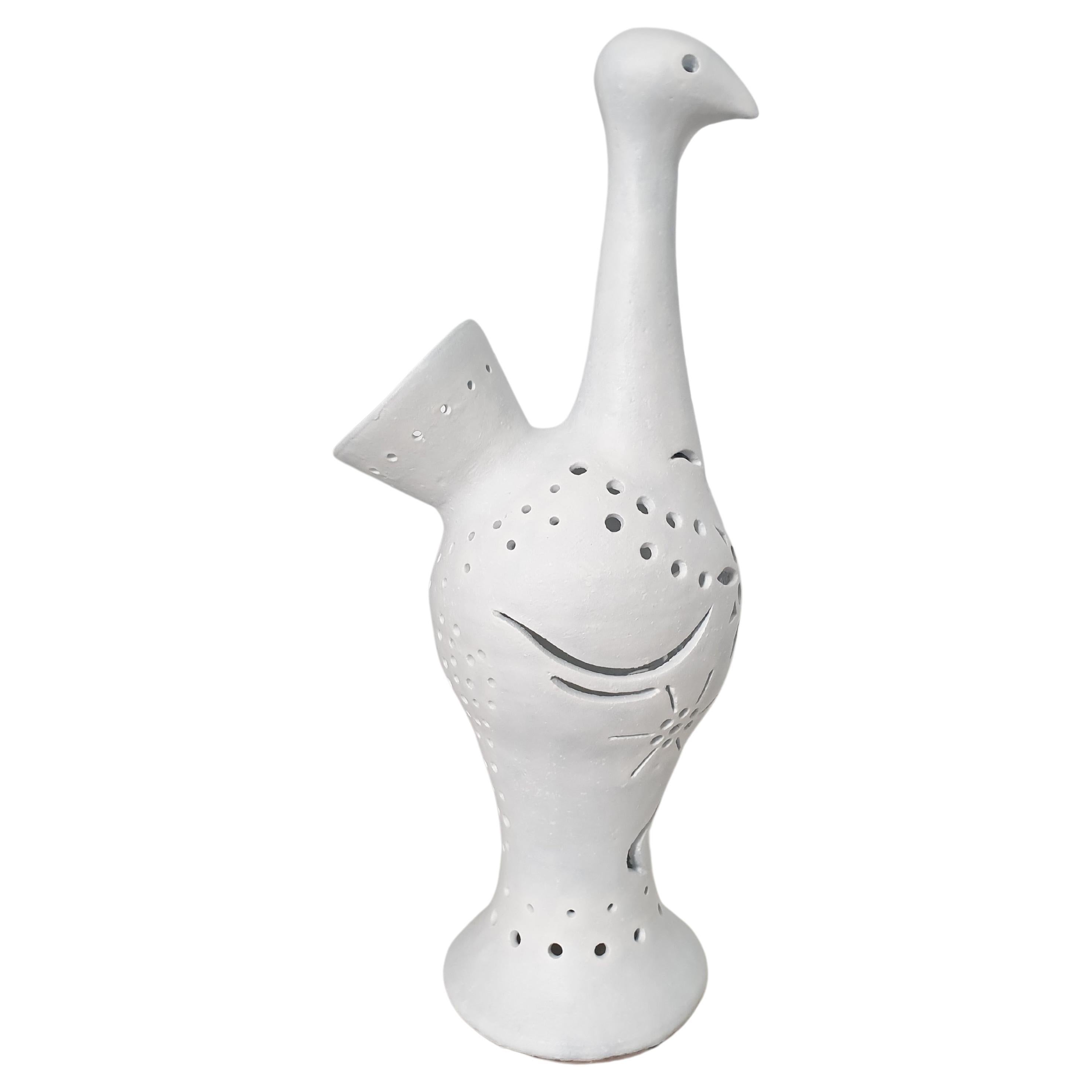 Large and imposing French white matt glazed ceramic lamp representing a stylized peacock. The lamp is unusual in that the lampholder is inside and the light streams out via the cuts in the surface of the bird. The lamp will be rewired by ourselves
