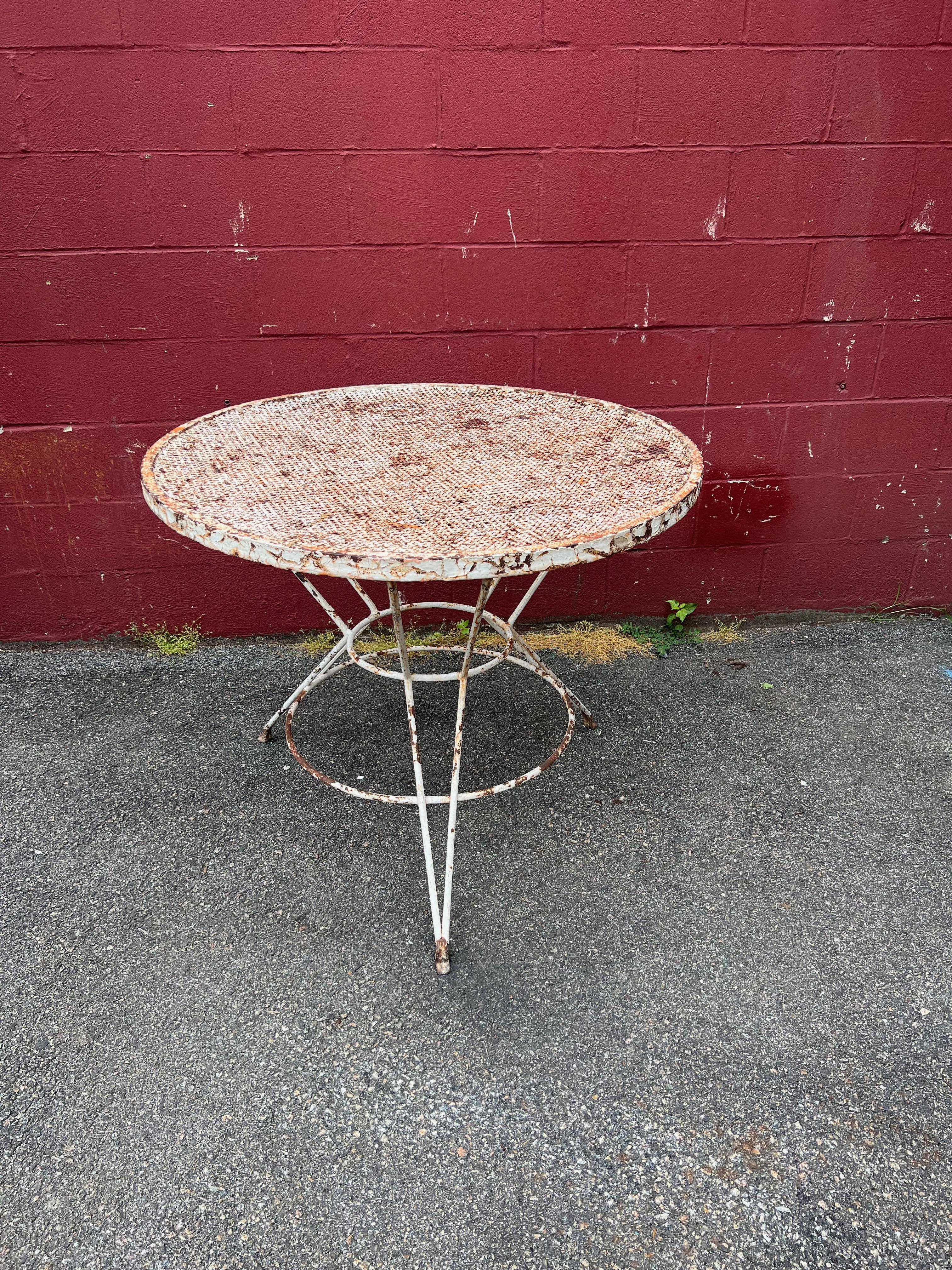 This beautiful French garden table perfectly embodies the mid-century modern style. The distressed paint adds a charming vintage touch, and the perforated top is both elegant and functional. The tripod base with a smaller upper circle and a larger