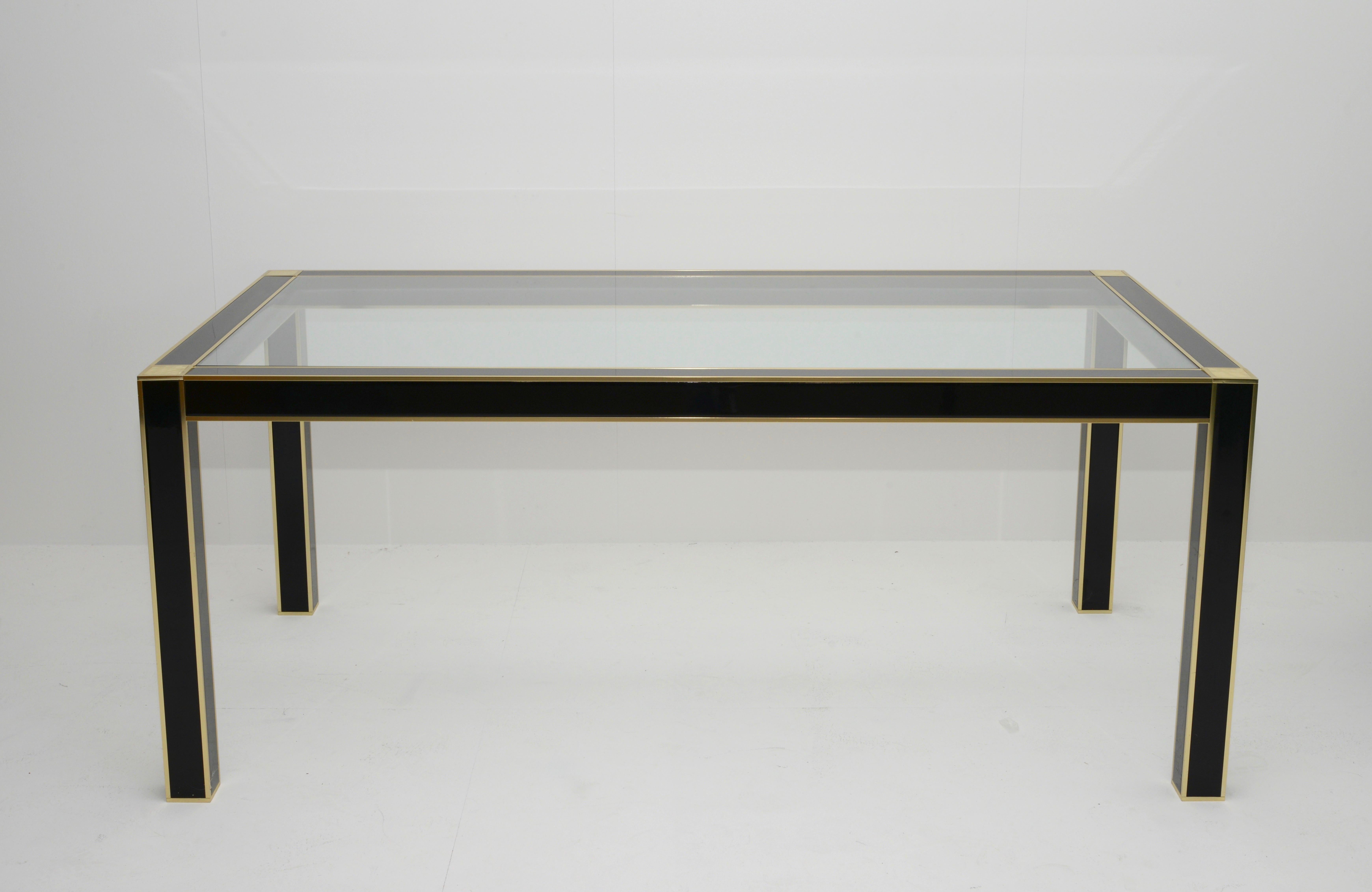 French Midcentury French lacquered dining table with clear glass by Pierre Cardin for Roche Bobois. This table is made of black lacquer on wood and features gilt brass trim throughout. The strong craftsmanship combined with the elegant lines made