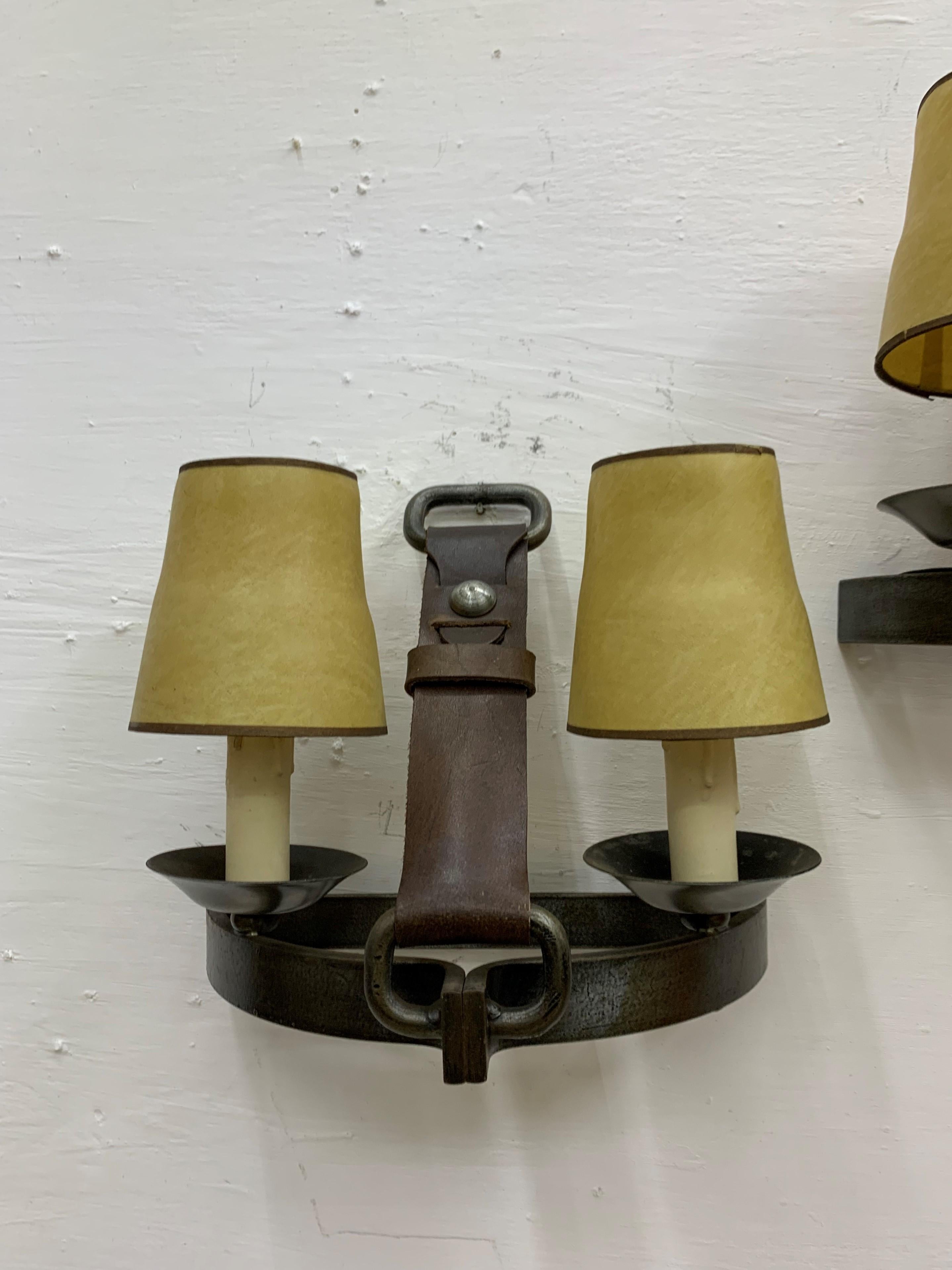 Three Mid-Century Modern sconces made in France, circa 1950. Manufactured in a horse riding stirrup shape attributed to French designer Jean Pierre Ryckaert and very much in the style of French modernist designer Jacques Adnet.
Both leather and