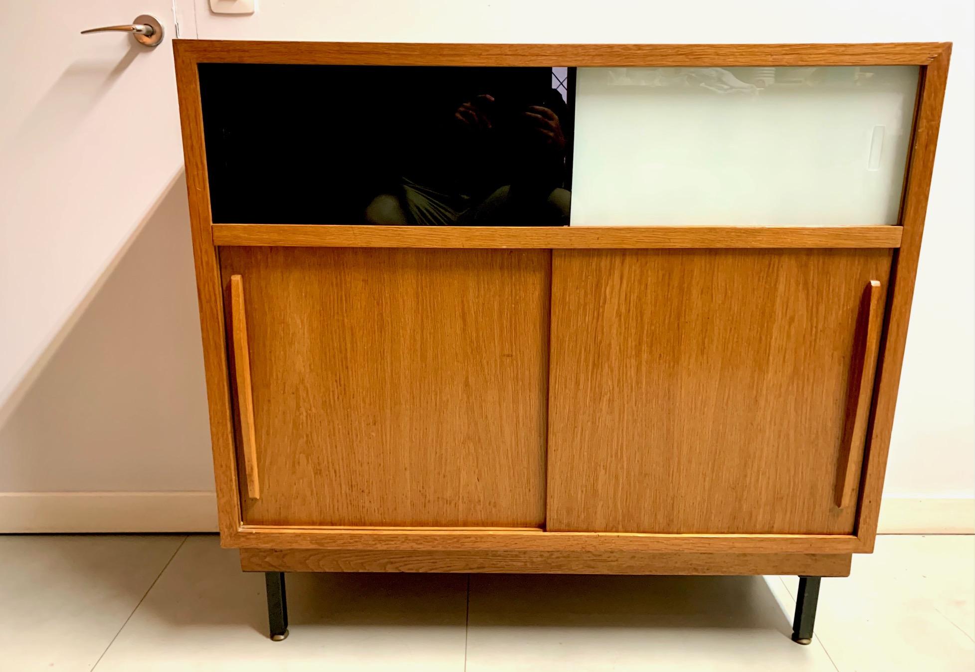 French cabinet from the 50s, in oak wood and lacquered glass in two colors, black and white, ending in metal legs.
The windows are sliding doors in the upper part, the lower part in oak wood, it is in perfect condition.