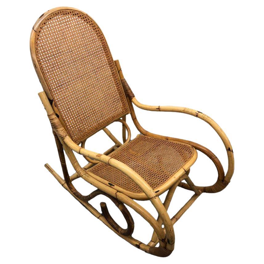 This rocking chair was made in France, circa 1960. it is made of rattan and has caning on the seat and back. The chair has a lovely patina and is in great shape. A perfect addition to any mid-century, boho and many other styles of