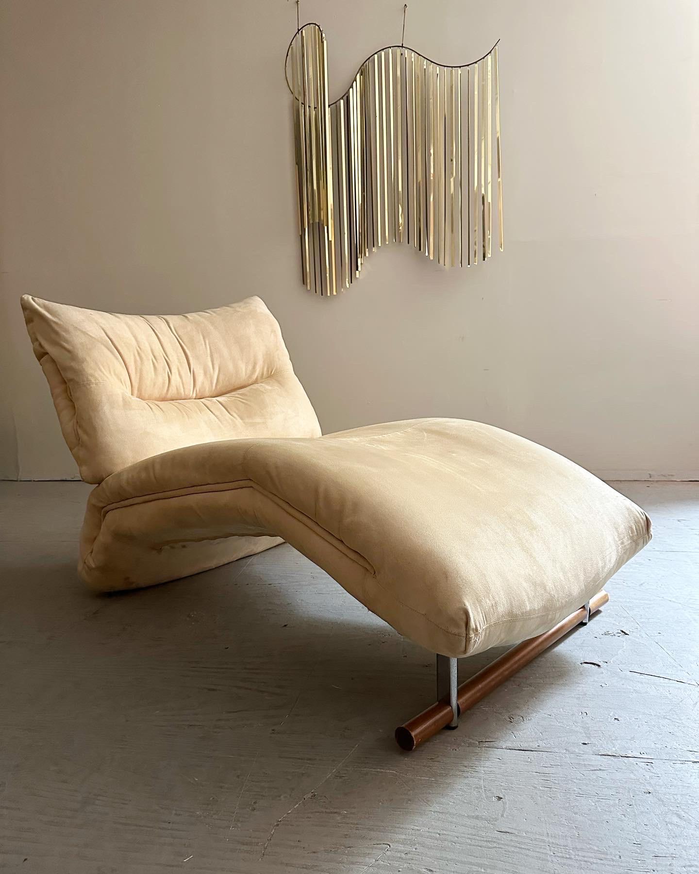 This beautifully designed french style chaise lounge features original beige suede upholstery with unique welt detailing. The chaise rests on a solid wood beam with chrome supports. Sure to be a standout addition to any modern living space.