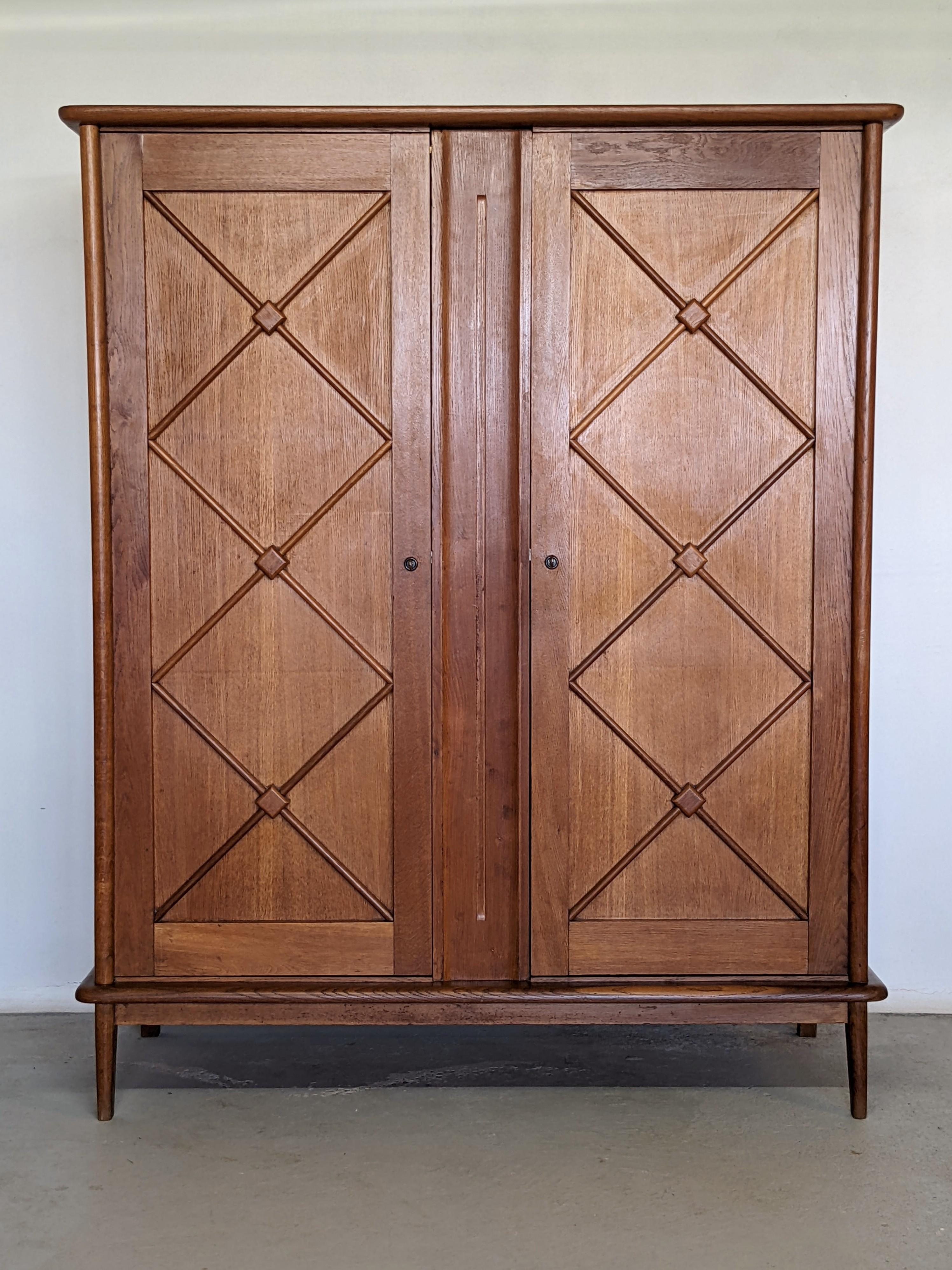 Elegant wardrobe in solid oak and oak veneer.
Made in France in the 1960s.

Geometric patterns on each doors.
3 Drawers adjustable in height on the left and a cloth rack on the right.
2 Keys included.

Beautiful wood grain.
