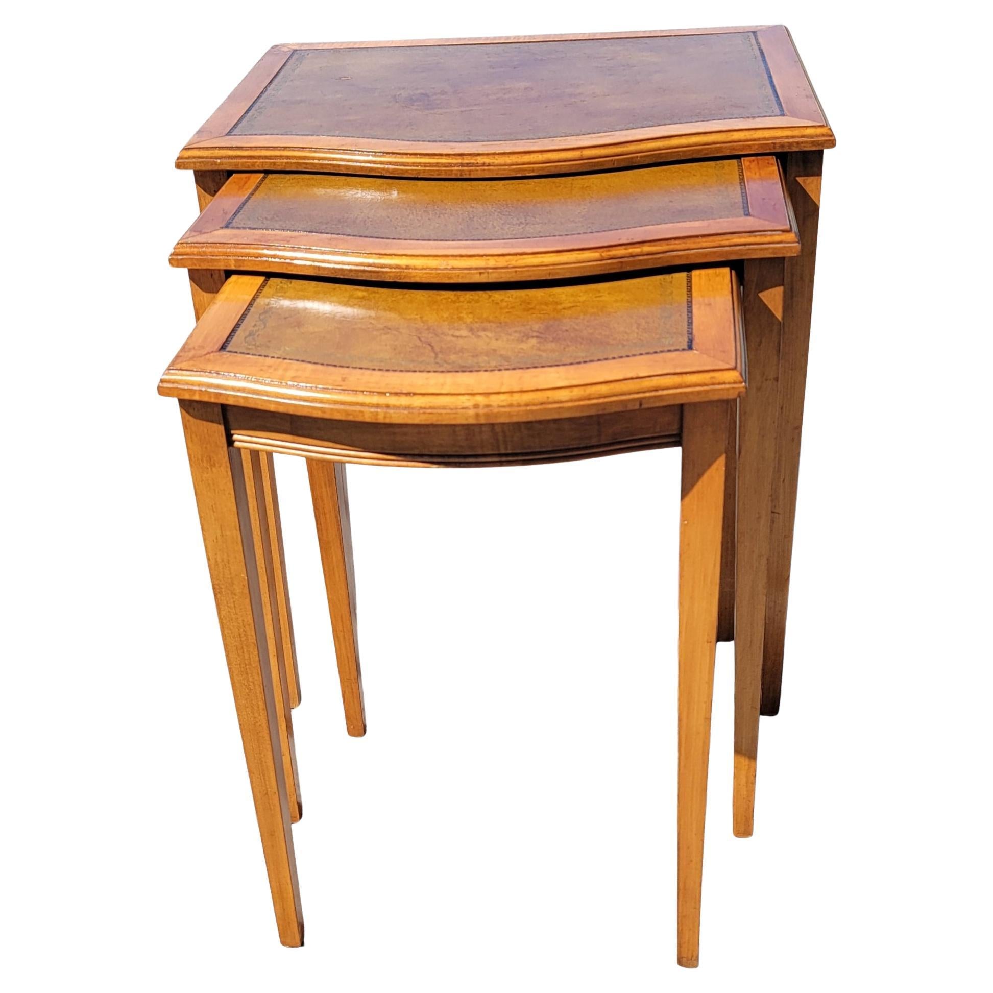Set of 3 Mid-Century Modern fruitwood nesting tables with leather and stenciled top. 
Larger table measures 22