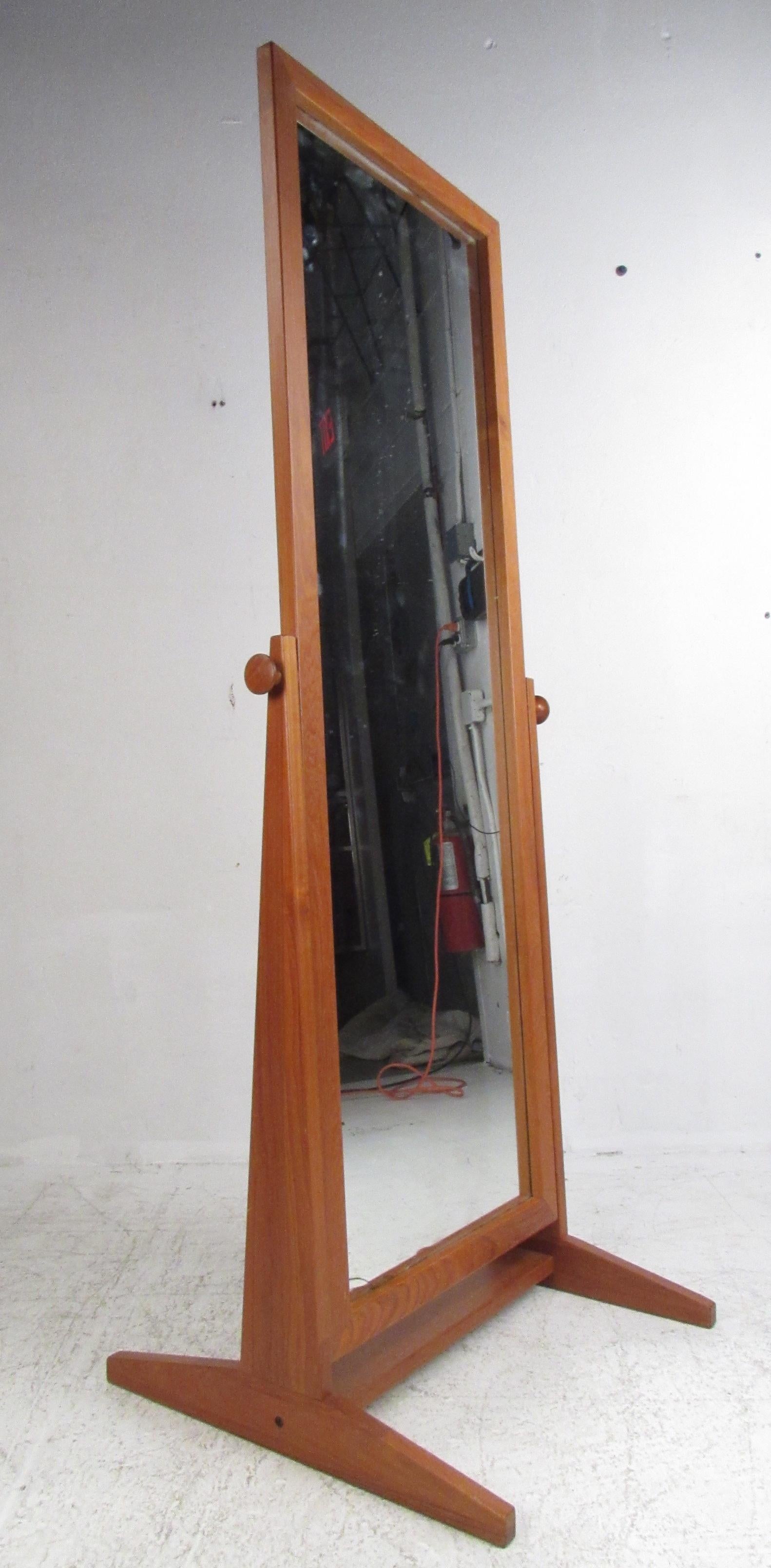 This beautiful vintage modern floor mirror features a teak frame with a floating full size mirror on a swivel. Stylish design with side supports that taper upward from the base creating an angular appearance. The sculpted knobs on each side easily