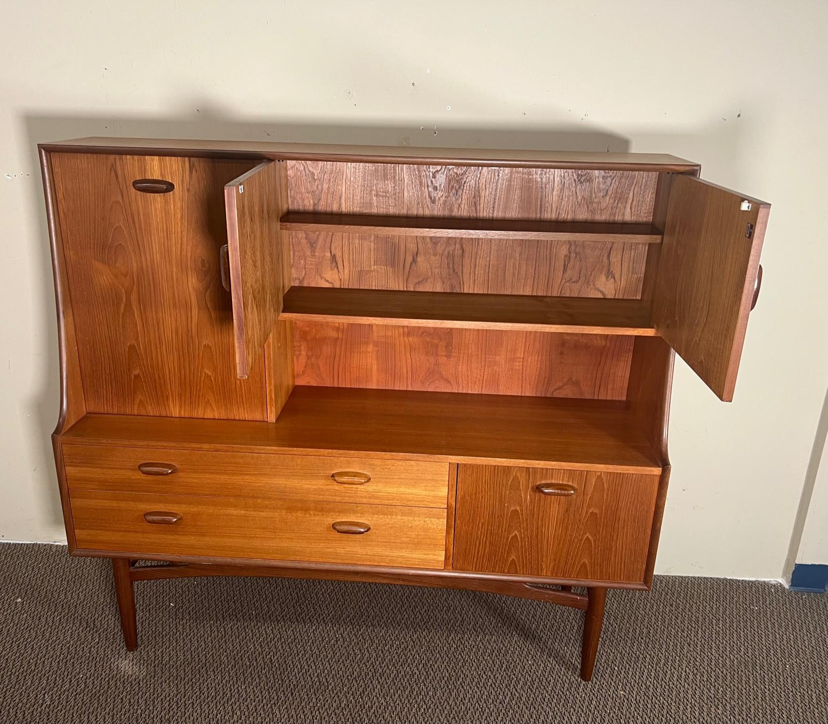 Mid-Century Modern versatile teak highboard by G Plan. Featuring an upper large drop down cabinet that can be used as a small desk and lower drop down cabinet or bar.
Very good condition. Screw hole on left side. Some spots on doors, chip on right